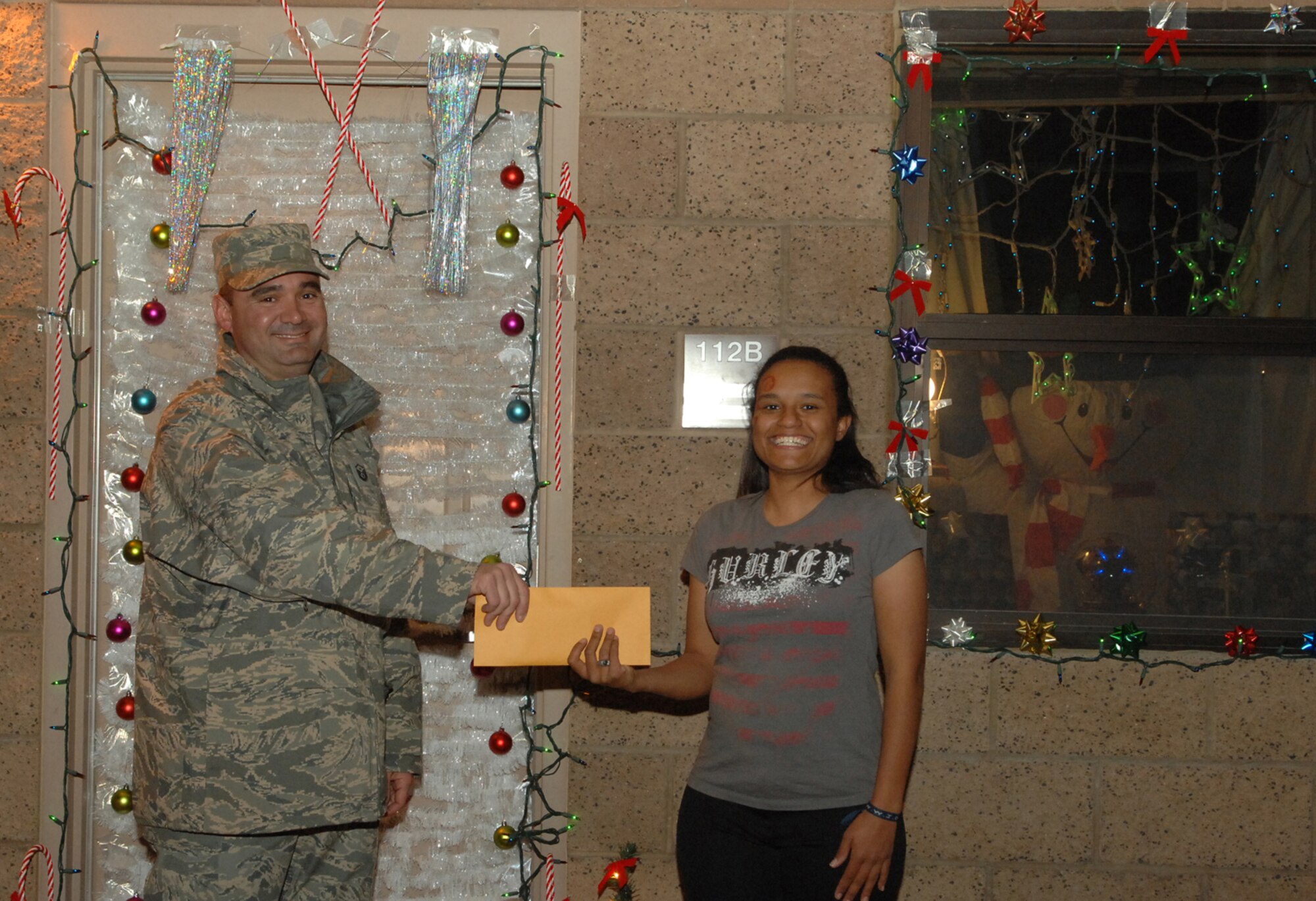 The Nellis AFB Holiday Decorating Contest is a chance for Airmen to show who has the most holiday spirit—Airman 1st Class Shaleena Hamilton, 99th Dental Squadron, dental technician, did just that when she received the first place award from Master Sgt. Stephen Ash, 99th Communications Squadron, first sergeant, with her “Snowman Wonderland” display, Dec. 20. Prizes for the contest included $200 for first place, $100 for second place and $65 plus a Play Station 2 game for third place. (U.S. Air Force photo by Senior Airman Nadine Y. Barclay)