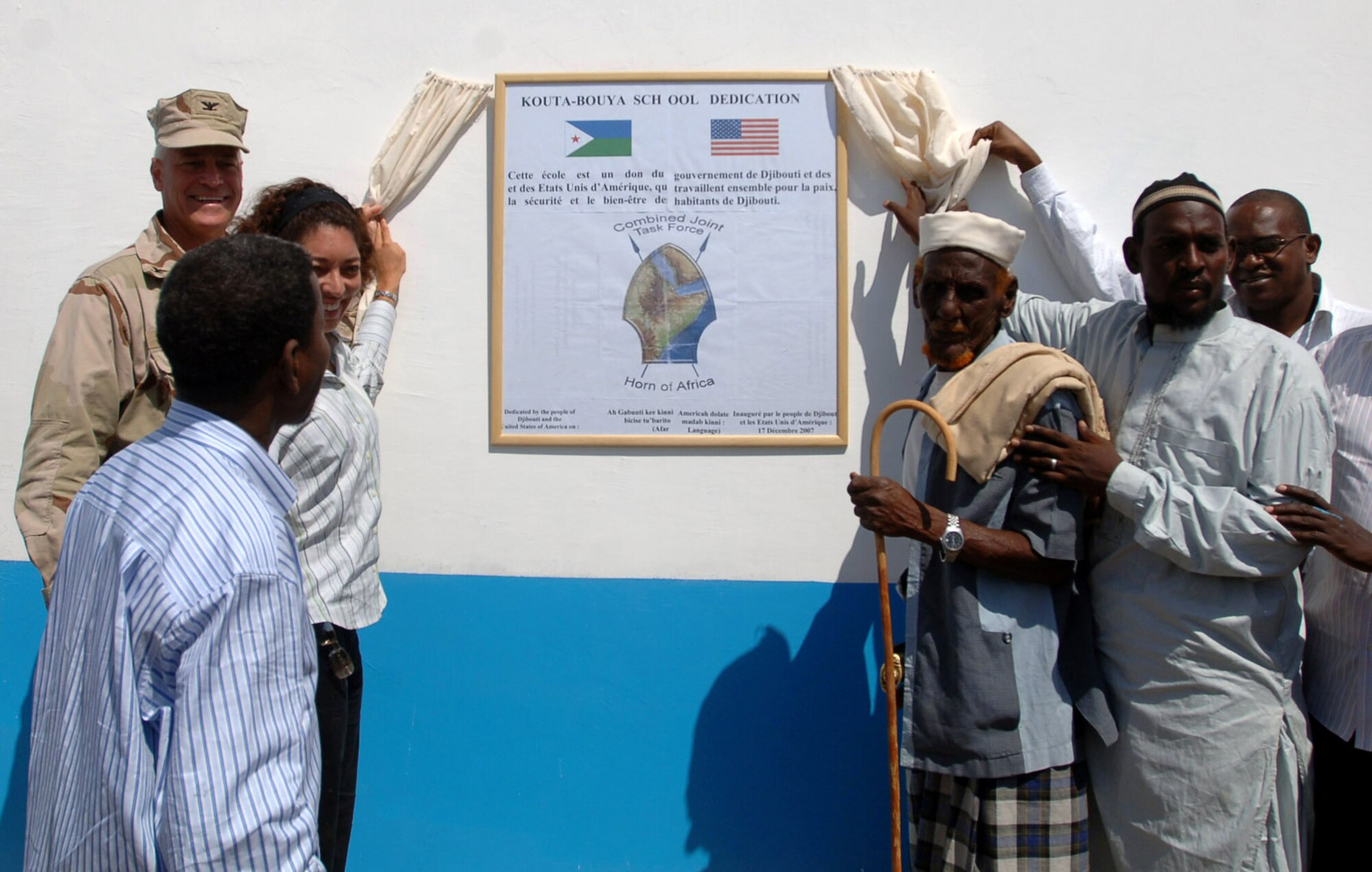 Navy Capt. Bob Wright, (back left to front) and Christy Stoner unveils the Kouta Bouya Primary School dedication plaque with the help of the school director, the village elder, the contractor and other community members before the dedication ceremony Dec. 17 in Djibouti. Captain Wright is the Combined Joint Task Force-Horn of Africa J-9 Strategic Communications director, and Ms. Stoner is the U.S. Embassy to Djibouti representative. (U.S. Navy photo/Petty Officer 1st Class Mary Popejoy) 
