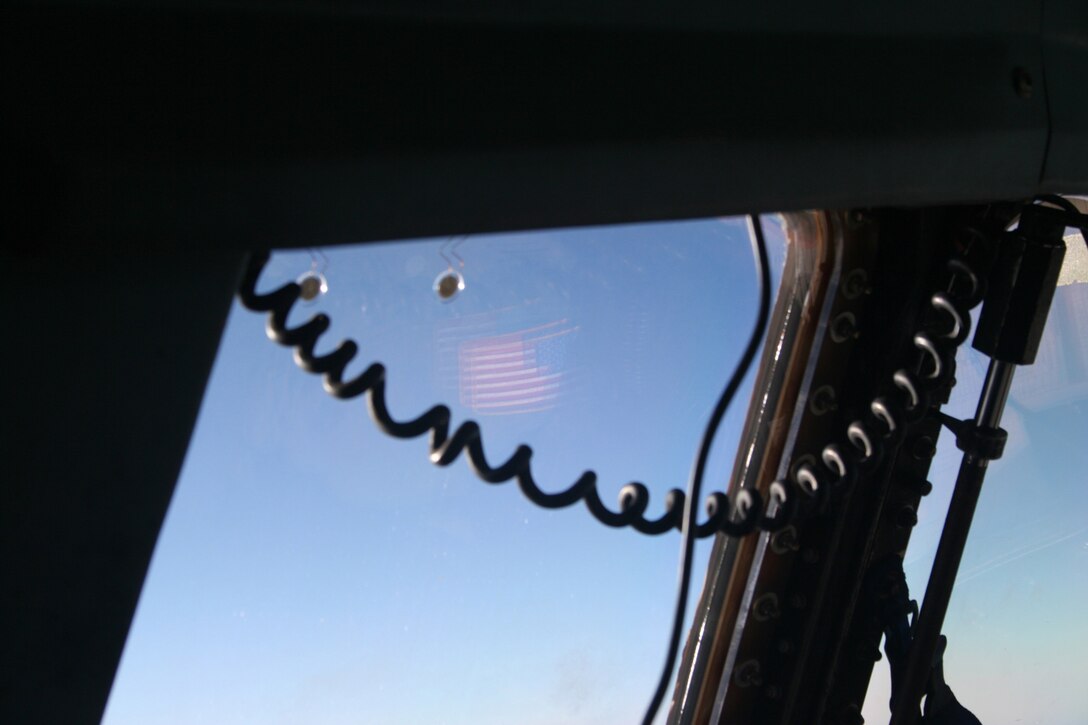 OVER THE ATLANTIC OCEAN --   An American Flag patch worn by the aircraft commander reflects in the flight deck window with clear skies outside.(U.S. Air Force photo/Maj. Ted Theopolos)