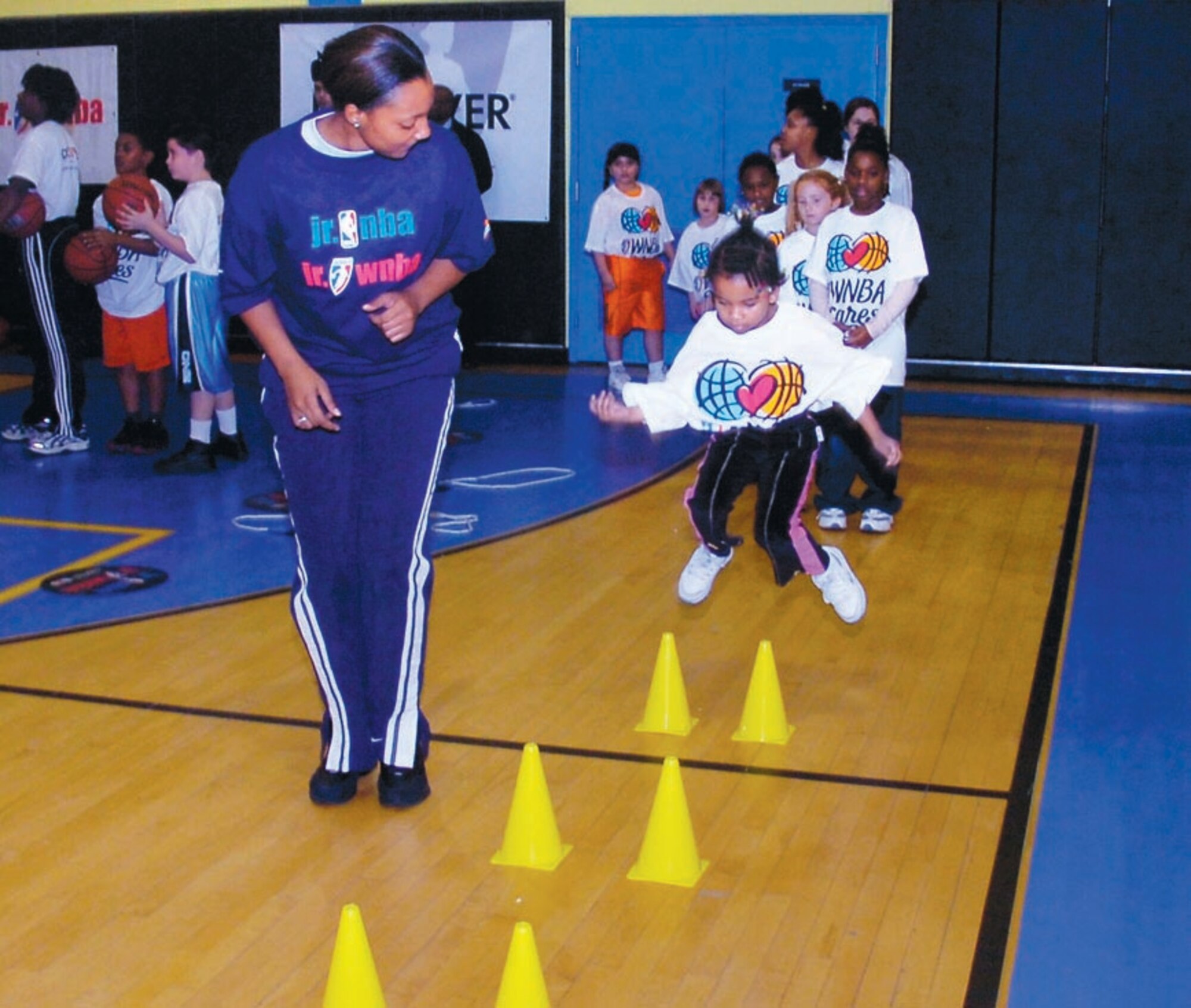 Airman 1st Class Sheena Edwards, 316th Mission Support Squadron customer service technician watches as a line of Andrews children jump over a row of cones during a strength and endurance drill at the Andrews Youth Center on Dec. 14. (US Air Force/Bobby Jones)