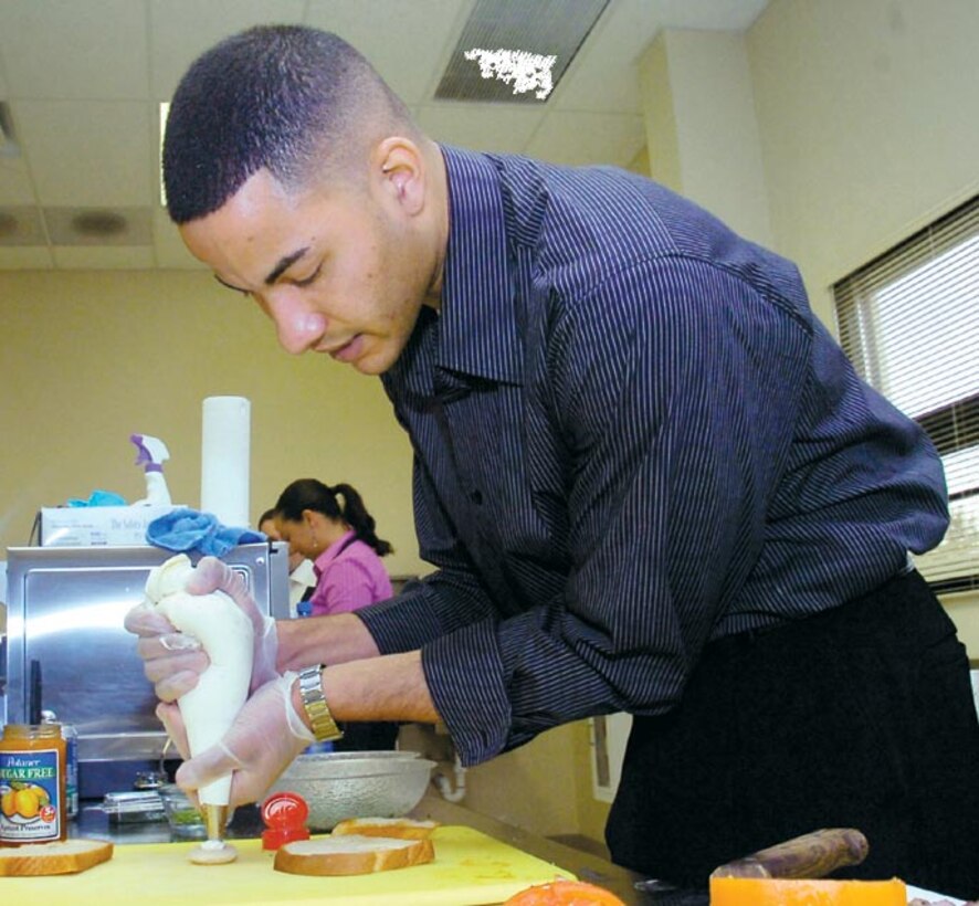Staff Sgt. Christopher Morlant prepares mini Beef Wellington appetizers for the invites guests of the Culinary Holiday hosted by the 89th Airlift Wing's flight attendants on Dec. 12. Sergeant Morlant is a flight attendant assigned to the 99th Airlift Squadron. (US Air Force/Bobby Jones)