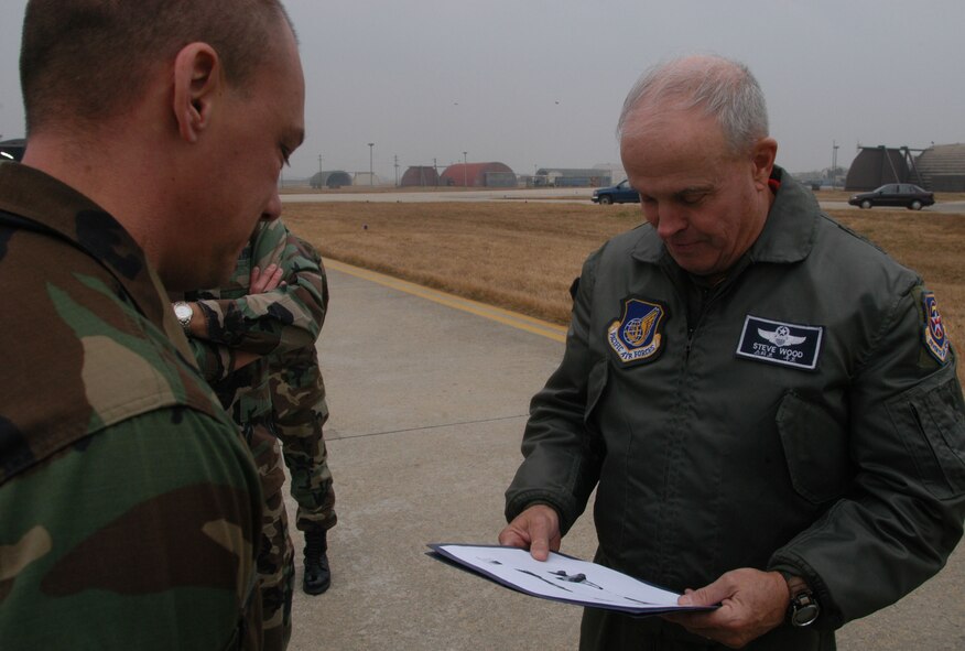 KUNSAN AIR BASE, South Korea -- Technical Sgt. Brian Coffel, 8th Maintenance Squadron shows the template used to paint an F-16 in an artic paint scheme to Lt. Gen. Stephen Wood, 7th Air Force commander during his visit to the base Dec. 21. Besides visiting Airmen on the flight line, the general is participating in the wing tree lighting ceremony and holiday party. (U.S. Air Force photo/Master Sgt. Sean P. Houlihan)