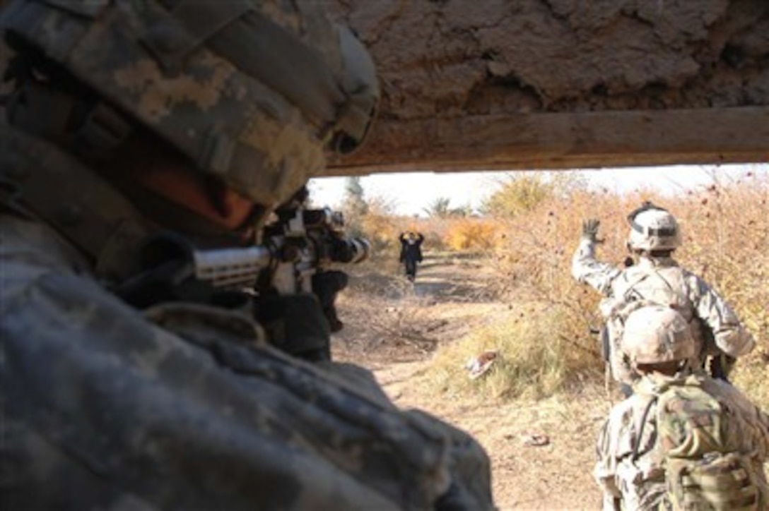 A U.S. Army soldier keeps his weapon aimed while fellow soldiers confront a local man with a weapon approaching them from the vine groves in Western Muqdadiyah, Iraq, on Dec. 12, 2007.  The soldiers are from Alpha Company, 2nd Battalion, 23rd Infantry Regiment, 3rd Brigade Combat Team, 2nd Infantry Division.  
