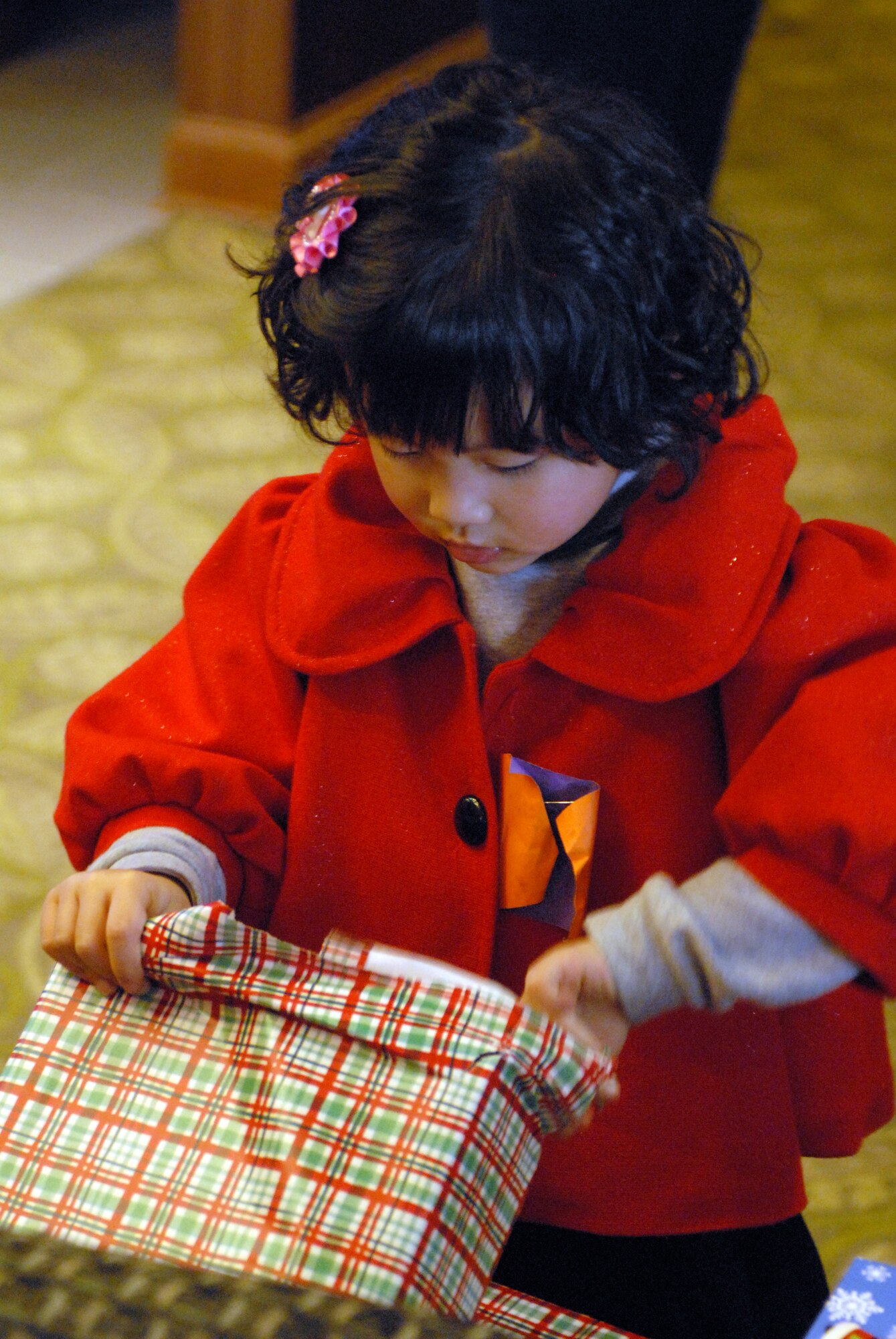 KUNSAN AIR BASE -- A child from the AeYuke orphanage opens a gift during a visit here Dec. 22.  Airmen from the 35th Fighter Squadron spent the afternoon with more than 65 children from a local orphanage touring an F-16 Fighting Falcon and flight simulator, handing out gifts, and playing.  The visit is part of the Good Neighbor Program which helps strengthen relations between Kunsan and the Korean community.  (U.S. Air Force photo/Senior Airman Steven R. Doty)