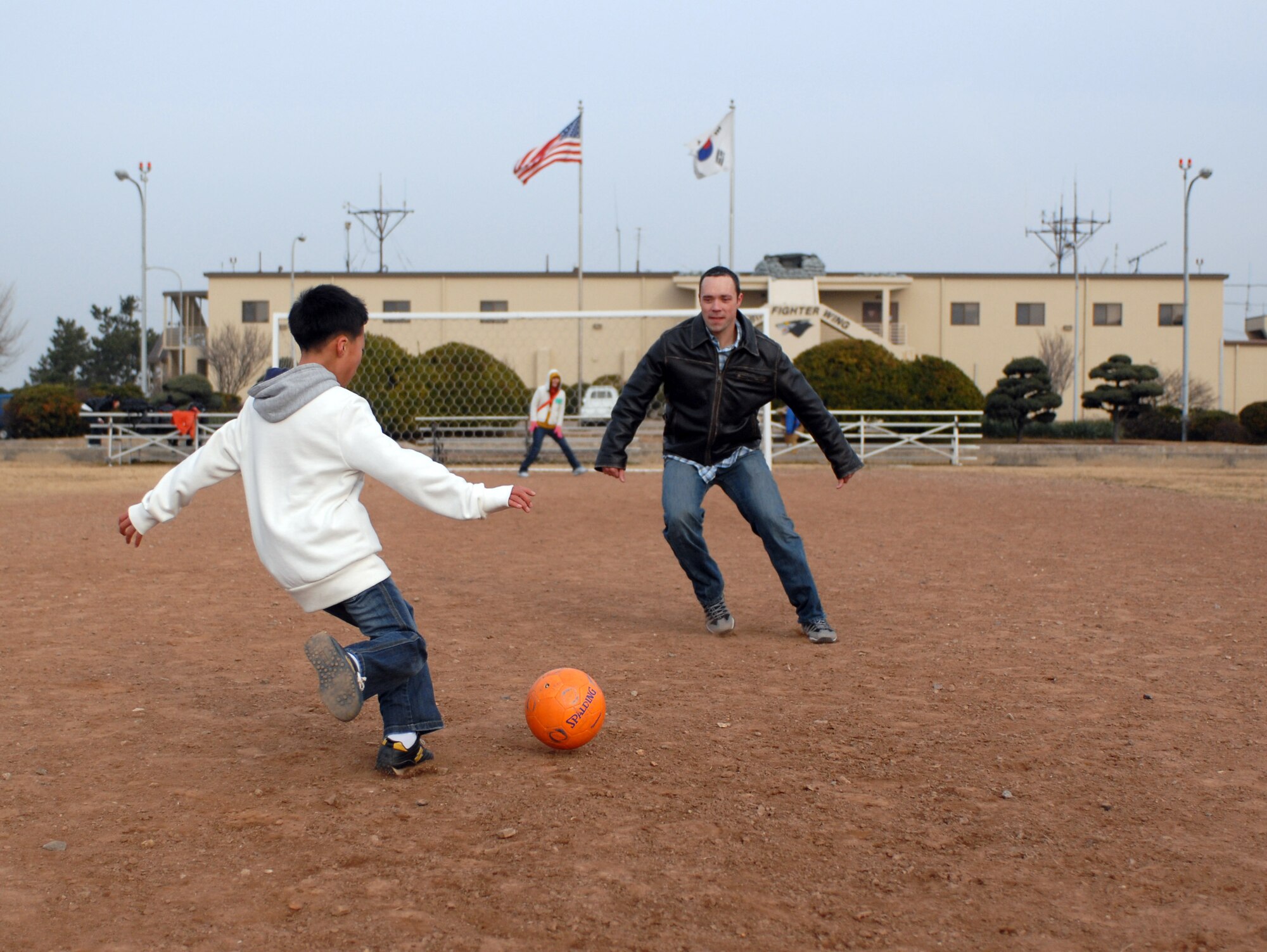 KUNSAN AIR BASE -- A child from the AeYuke orphanage and Captain Greg Jenkins, F-16 pilot from the 35th Fighter Squadron, play a game of soccer during a visit here Dec. 22.  Airmen from the 35th Fighter Squadron spent the afternoon with more than 65 children from a local orphanage touring an F-16 Fighting Falcon and flight simulator, handing out gifts, and playing.  The visit is part of the Good Neighbor Program which helps strengthen relations between Kunsan and the Korean community.  (U.S. Air Force photo/Senior Airman Steven R. Doty)