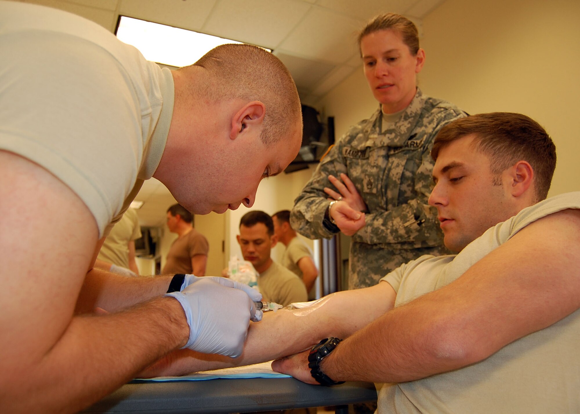FORT BRAGG, N.C. -- Air Force 1st Lt. Marc Quesnel administers a saline lock, more commonly known as an IV, to Air Force 1st Lt. Adam Lazar during Combat Lifesaver training Dec. 16 while under the expert supervision of an Army combat medic. Lieutenant Quesnel, Team Paktia’s civil engineer, is deployed from Seymour Johnson Air Force Base, N.C. Lieutenant Lazar is deployed from Barksdale AFB, La., and serving as Team Zabul’s civil engineer. Current combat zone medical protocol calls for administering a saline lock to combat casualties because it’s easier to accomplish while veins are still viable rather than later when time might be short and the veins collapsed from blood loss. (U.S. Air Force photo/Capt. Ken Hall)