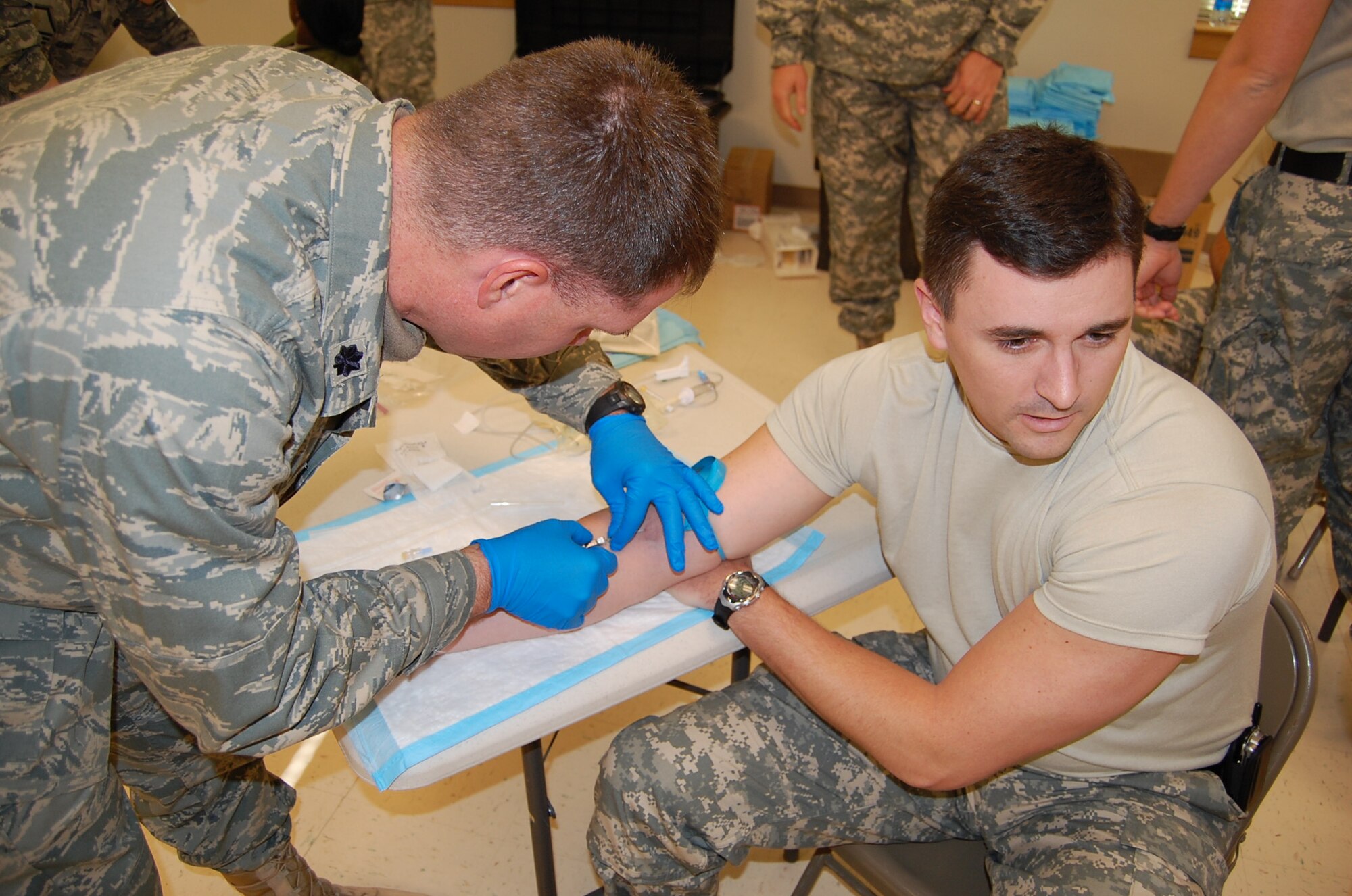 FORT BRAGG, N.C. -- Air Force Lt. Col. Brett Sharp administers a saline lock, more commonly known as an IV, to Army Capt. (P) Mike Hahn during Combat Lifesaver training Dec. 16 while under the expert supervision of an Army combat medic. Colonel Sharp, an Air Battle Manager, deployed from Air Combat Command headquarters at Langley AFB, Va., to command the Paktia PRT. Captain Hahn is an OH-58D Kiowa helicopter pilot deployed from Fort Rucker, Ala., and he will serve as the team’s operations officer. Current combat zone medical protocol calls for administering a saline lock to combat casualties because it’s easier to accomplish while veins are still viable rather than later when time might be short and the veins collapsed from blood loss. (U.S. Air Force photo/Capt. Ken Hall)