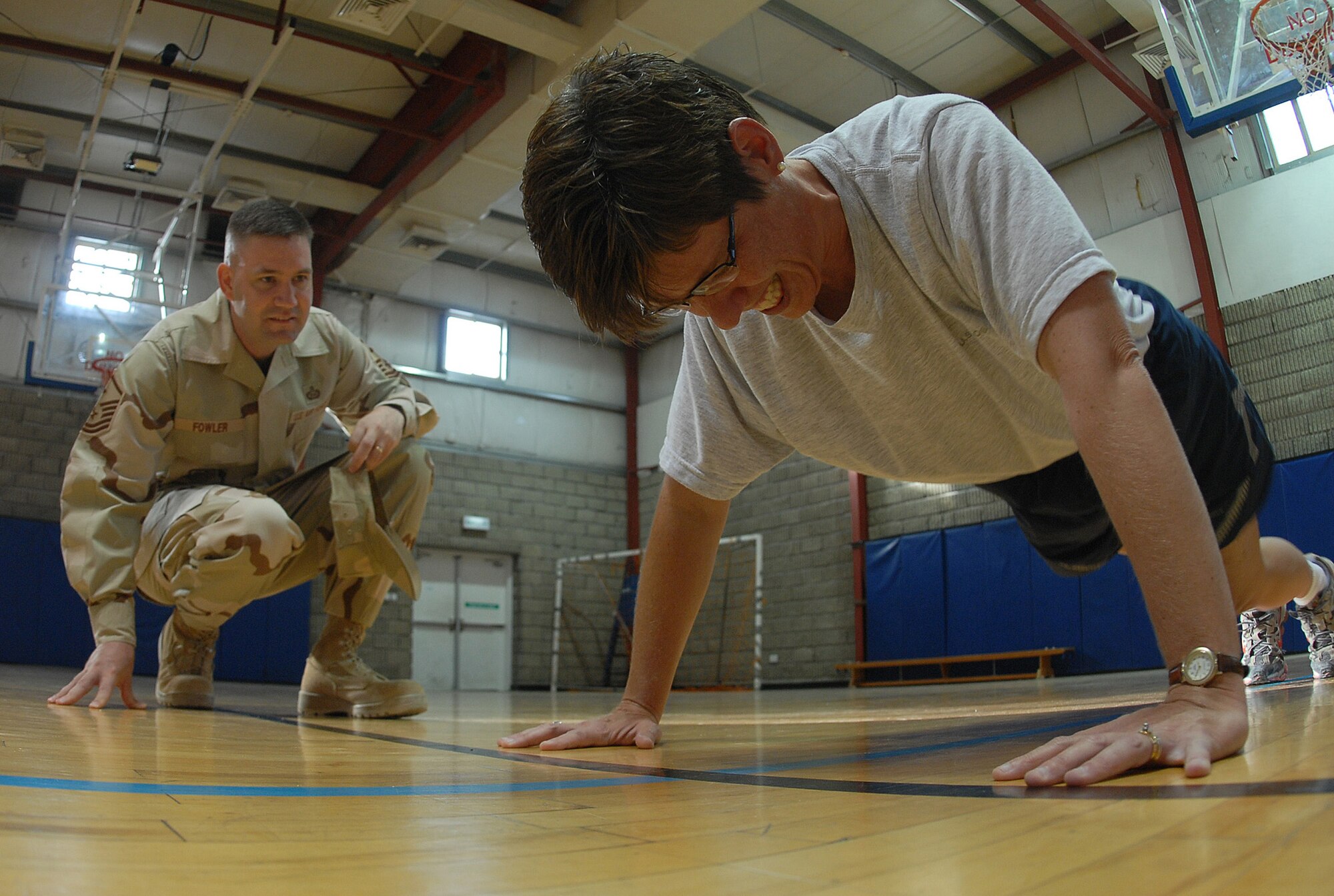 SOUTHWEST ASIA - Master Sgt. Julie Privette, 379th Expeditionary Services Squadron, pushes out 155 push ups  Dec. 22 for a fund-raising event hosted by the Desert Diamond's at a Southwest Asia air base Dec. 22. Master Sgt. Christopher Fowler, 379th Expeditionary Aircraft Maintenace Squadron first sergeant, encourages and counts Sergeant Privette's push ups. Sergeant Privette is deployed from Royal Air Forces Mildenhall, United Kingdom. Sergeant Fowler is deployed from Moutain Home, Air Force Base, Idaho. (U. S. Air Force photo/Staff Sergeant Douglas Olsen)