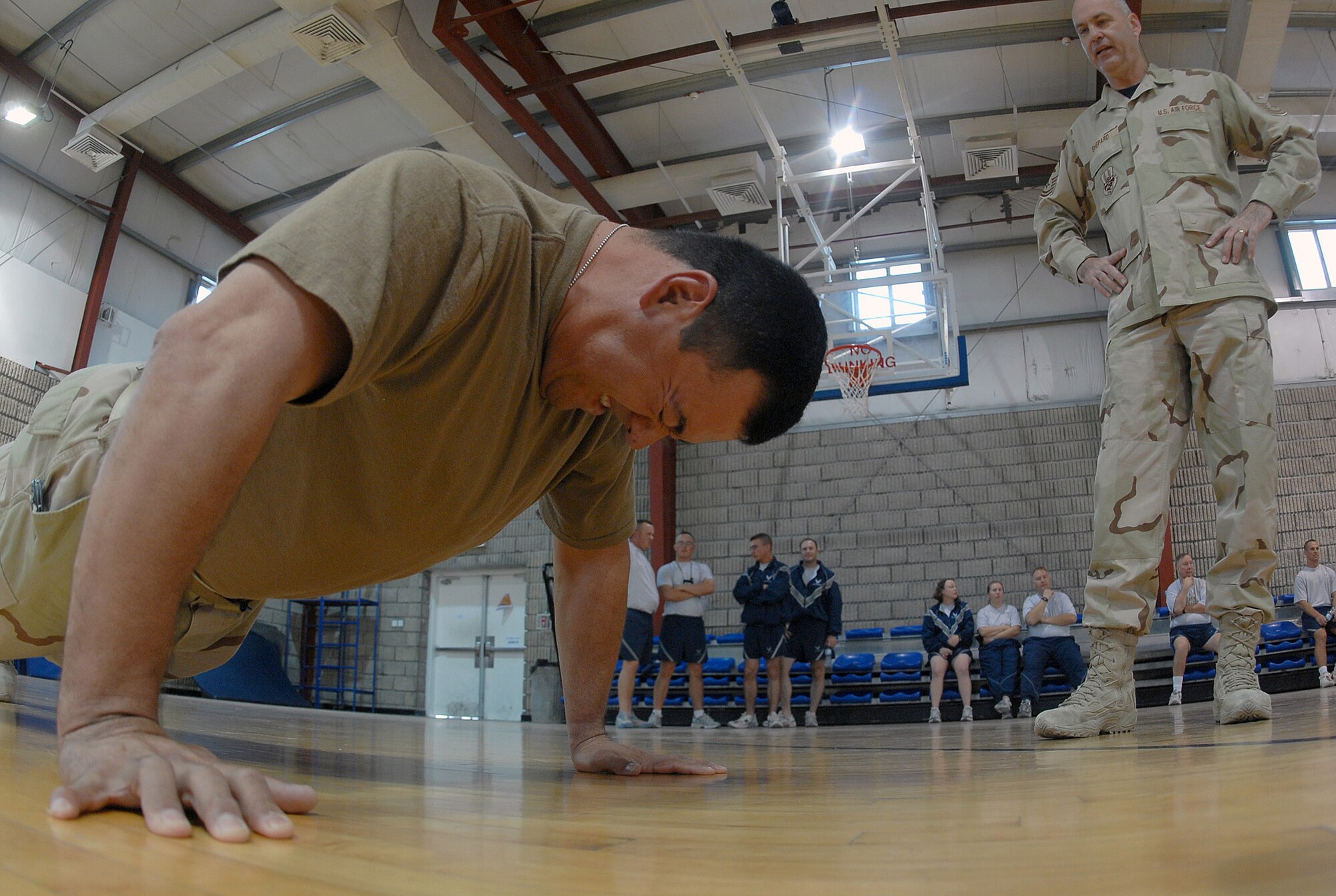 SOUTHWEST ASIA -  Master Sgt. Isidro De La Rosa, 379th Expeditionary Services Squadron, does push ups for a fund-raising event sponsored by the Desert Diamonds Dec. 22 at a Southwest Asia air base. Senior Master Sgt. Doug Shepard encourages and counts Sergeant De La Rosa's push ups. Sergeant De La Rosa is deployed from Buckley Air Force Base, Colo. His hometown is Greeley, Colo. Sergeant Shepard is deployed from Youngstown Air Reserve Base, Ohio. (U.S. Air Force photo/Staff Sergeant Douglas Olsen)
