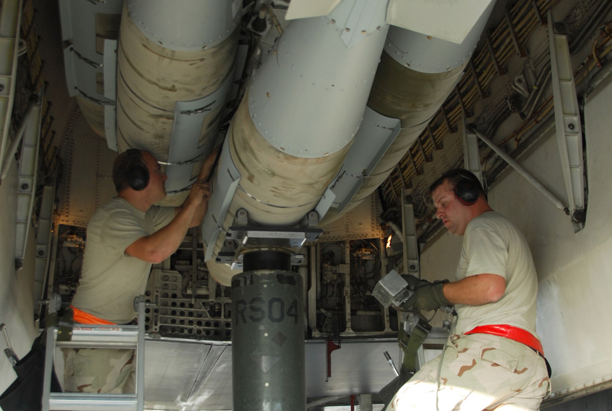 SOUTHWEST ASIA - Staff Sgt. Brandon Neitz (left) and Tech. Sgt. James Sheldon, 379th Expeditionary Maintenance Squadron, load 2,000 pound bombs on a B-1B Lancer Dec. 21 to prepare it for a mission at a Southwest Asia air base. Both sergeants are deployed from Dyess Air Force Base, Texas. (U.S. Air Force photo/Staff Sgt. Douglas Olsen)