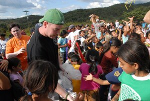 COMAYAGUA, Honduras -- Air Force Senior Airman Evan McIntosh, a 612th Air Base Squadron firefighter, hands out miniature soccer balls to children here during a toy giveaway Dec. 23.  A toy drive was organized by the Joint Task Force-Bravo Chapel and the gifts were donated by the families of servicemembers stationed at Soto Cano Air Base, Honduras.  (U.S. Air Force photo by Tech. Sgt. Sonny Cohrs) 