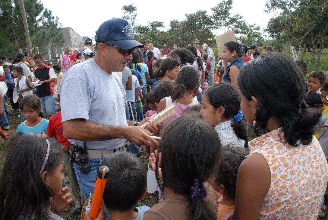 COMAYAGUA, Honduras - Herberth Gaekel, 612th Air Base Squadron fire inspector, hands out rulers to Honduran children waiting in line to receive toys from Joint Task Force-Bravo servicemembers here Dec. 23.  The toy drive was organized by the JTF-Bravo Chapel and the gifts were donated by the families of servicemembers stationed at Soto Cano Air Base, Honduras.  (U.S. Air Force photo by Tech. Sgt. Sonny Cohrs) 