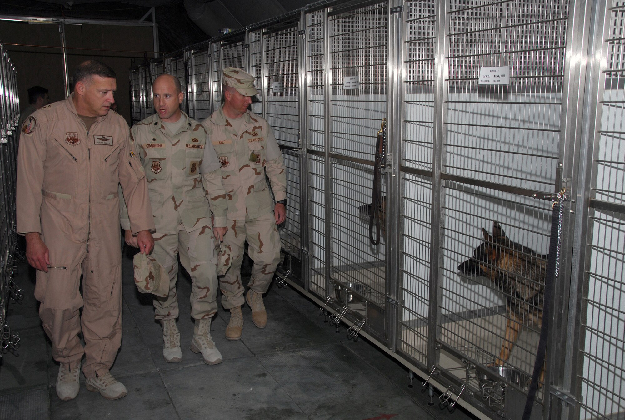 SOUTHWEST ASIA - Lt. Col. Michael Gimbrone and Tech. Sgt. John Self, 379th Expeditionary Security Forces Squadron, gives Lt. Gen. Gary North, 9th Air Force commander, a tour of the K-9 kennels during the general's visit to a Southwest Asia  air base Dec. 23. (U. S. Air Force photo/Staff Sgt. Douglas Olsen)