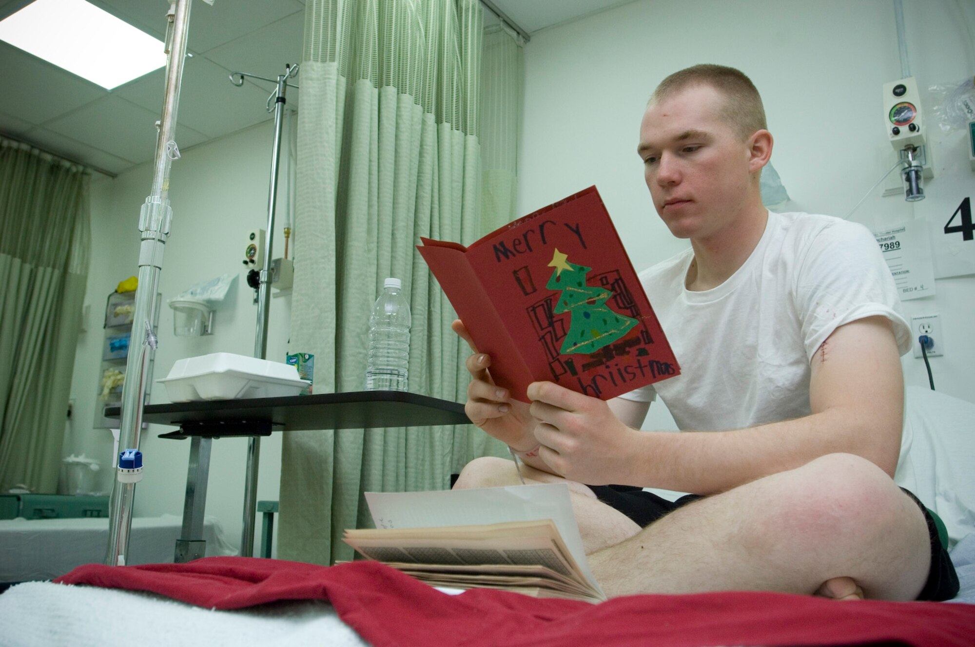 BALAD AIR BASE, Iraq -- Army Pvt. Zachariah Harvey, an artilleryman deployed to Camp Taji, reads a holiday card from Girl Scout Troop #47534, Cincinnati, Ohio on Dec. 24. Private Harvey, a native of Le Roy, Minn., was injured by a gun shot wound north of Baghdad on Dec. 23. He is recovering at the Air Force Theater Hospital here. The hospital is the medical hub for all of Iraq and the only facility capable of providing a full spectrum of medical care for trauma patients. Private Harvey is deployed from Rose Barracks, Vilsek, Germany. (U.S. Air Force photo/Tech. Sgt. D. Clare)