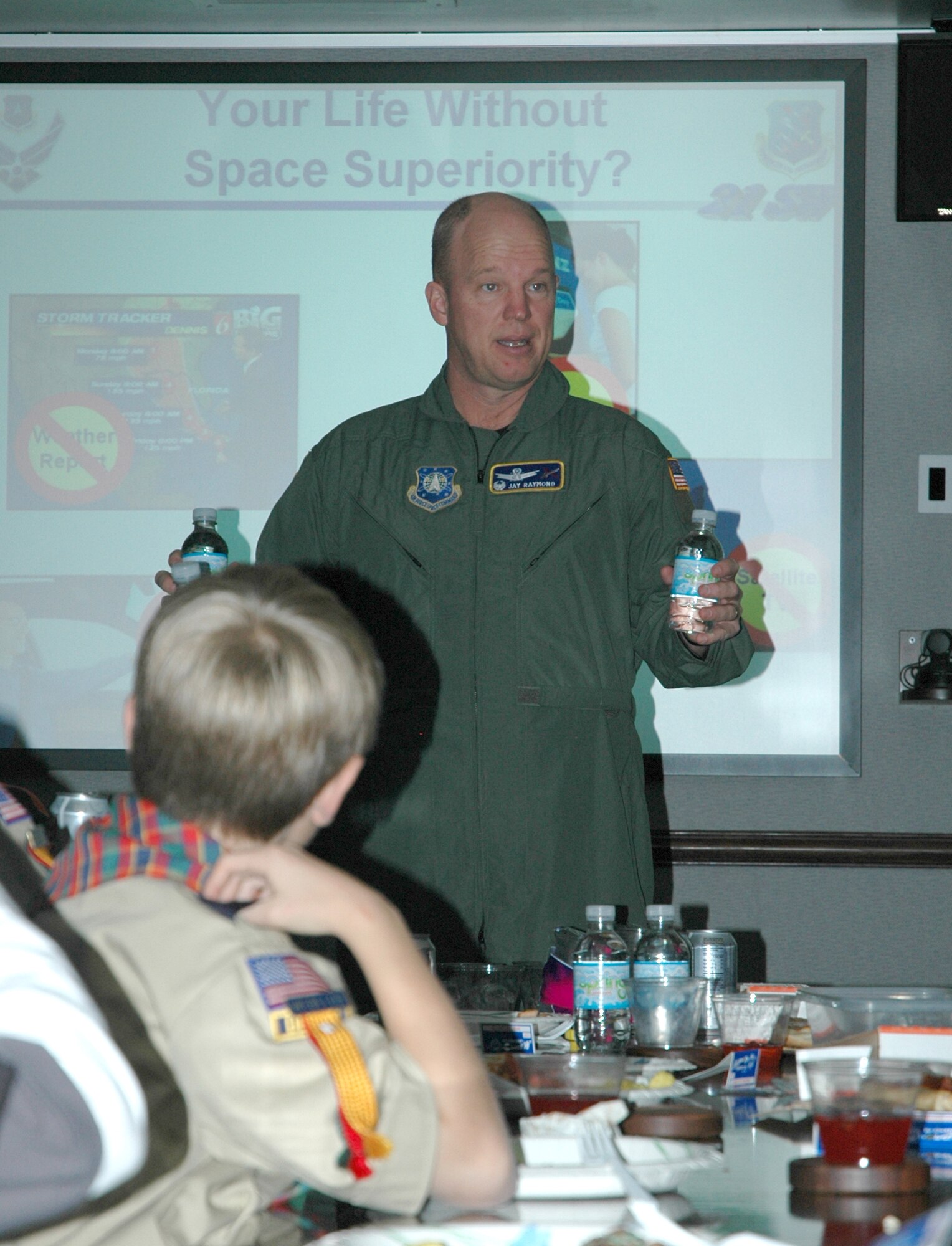 Col. Jay Raymond, 21st Space Wing commander, uses bottles of water to describe global-positioning system satellite orbits to scouts of Cub Scout Pack 461 Dec. 21. The scouts toured the 21st SW and the Cheyenne Mountain Complex, learning about the space wing’s mission and the role of Cheyenne Mountain in protecting the United States. (U.S. Air Force photo/Senior Airman Stephen Collier)