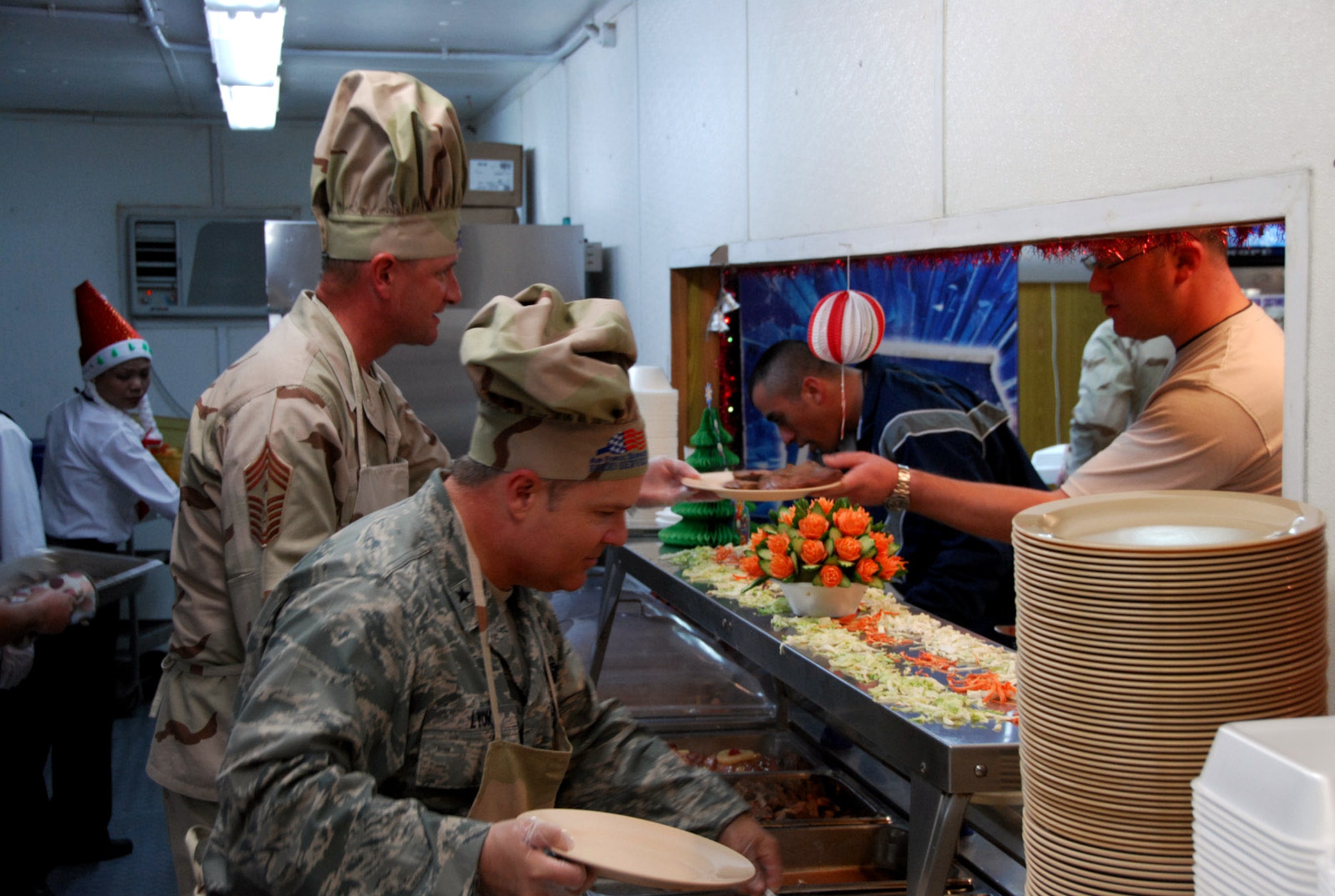 Brig. Gen. Charles W. Lyon and Chief Master Sgt. Lloyd Hollen serve dinner to deployed troops Dec. 25 at a Southwest Asia air base. General Lyon is the 379th Air Expeditionary Wing commander, and Chief Hollen is the 379th AEW command chief. (U.S. Air Force photo/Staff Sgt. Douglas Olsen) 
