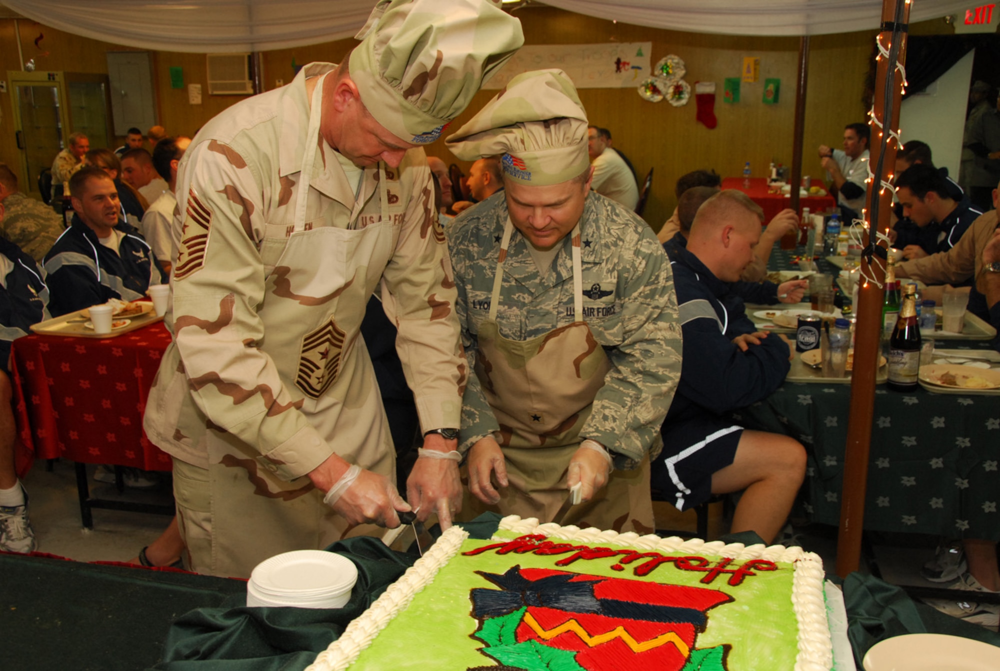 SOUTHWEST ASIA - Brig. Gen. Charlie Lyon, 379th Air Expeditionary Wing commander, and Chief Master Sgt. Lloyd Hollen, 379th AEW command chief, cut the holiday cake during Christmas dinner at a Southwest Asia air base Dec. 25. (U. S. Air Force photo/Staff Sgt. Douglas Olsen)