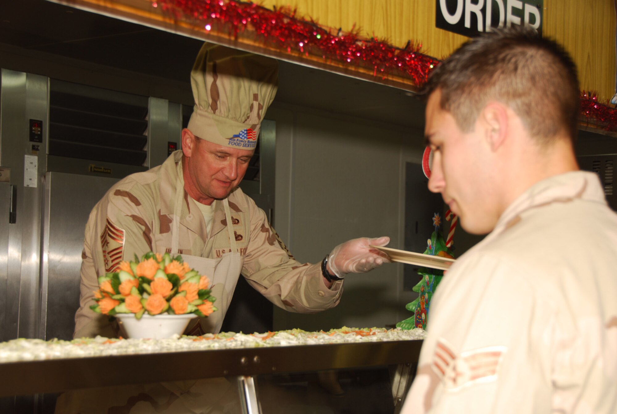 SOUTHWEST ASIA - Chief Master Sgt. Lloyd Hollen, 379th Air Expeditionary Wing command chief, serves Christmas dinner to deployed troops at a Southwest Asia air base Christmas day. (U.S. Air Force photo/Staff Sgt. Douglas Olsen)