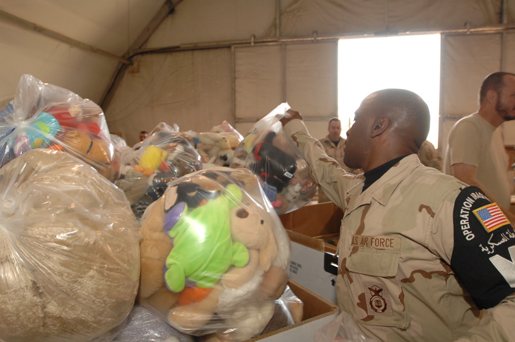 ALI AIR BASE, Iraq -- Tech. Sgt. Paul Wright tosses a bag of toys into the third crate filled with even more toys Dec. 22 in support of Operation Iraqi Child led by the Focus 5/6 and Top 3 councils. In just over a month, Airmen on base collected thousands of school supply items, soccer balls, stuffed animals and toys from back home. Airmen from across all eight squadrons spent a few hours sorting all the donated items which the office of special investigations will give to Iraqi families in the An Nasiriyah area villages. Sergeant Wright is assigned to the 407th Expeditionary Provost Marshal Office and is deployed from Spangdahlem Air Base, Germany. (U.S. Air Force photo/Airman 1st Class Jonathan Snyder)