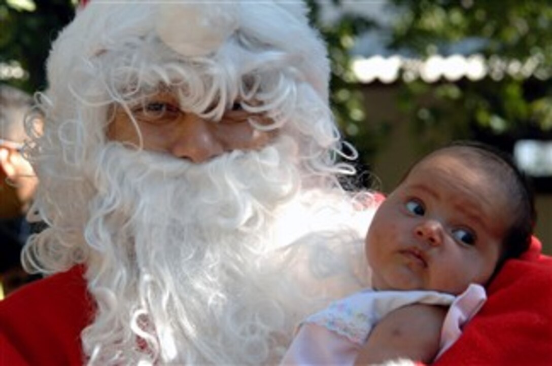 U.S. Air Force Tech. Sgt. Norman Padilla Cruz plays Santa Claus for an orphan girl from  Comayagua, Honduras, Dec. 15, 2007. The airmen of the 1st Special Operations Wing will deliver more than 9,000 pounds of Christmas packages to hundreds of Honduran orphans this holiday season.  