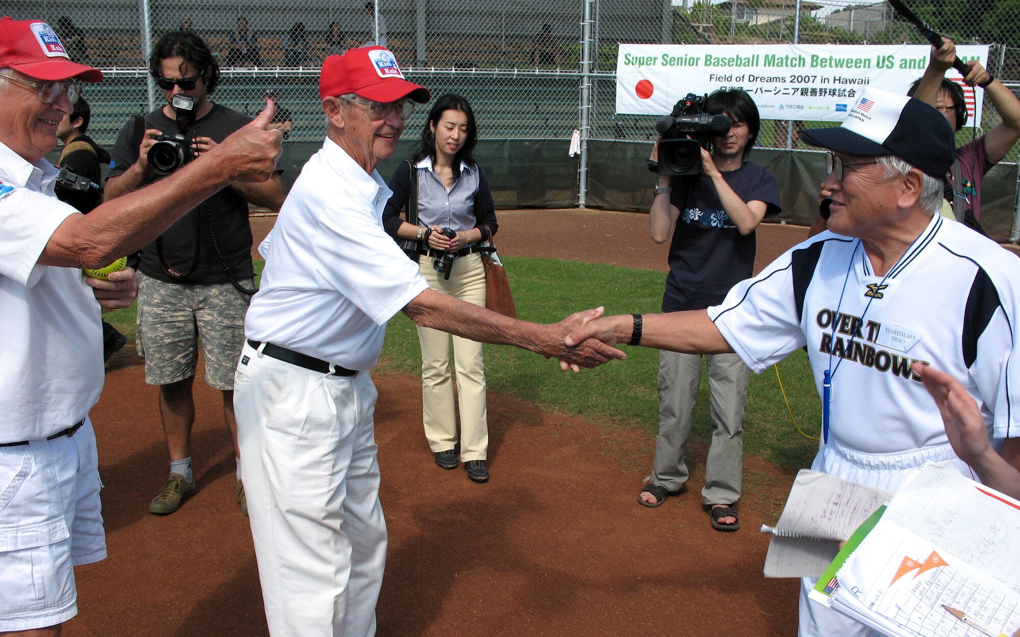 84-year-old Pete Murphy, captain of the Kids & Kubs senior softball team from St. Petersburg, Fla., and 74-year-old Yoshimasa Iwao, captain of the Over the Rainbows senior softball team from Japan, shake hands before their game Dec. 19 at Hans L'Orange Park in Waipahu, Hawaii. The two teams, comprising WWII veterans, met here to make peace with the past and play this historic game. The Kids & Kubs won the game 14-2. (U.S. Air Force photo/Tech. Sgt. Chris Vadnais)