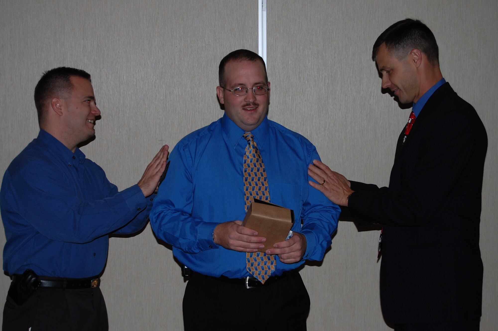Staff Sgt. David Megeath, 436th Maintenance Operations Squadron, is tacked on by Col. Steve Harrison, 436th Airlift Wing commander, and Maj. Andy Levien, 436th MOS commander. Sergeant Megeath unwrapped what he thought was a party gift to be technical sergeant stripes and coin at his squadron's Christmas Party Dec. 21. (U.S. Air Force photo/ Chief Master Sgt. Howard Heisey)