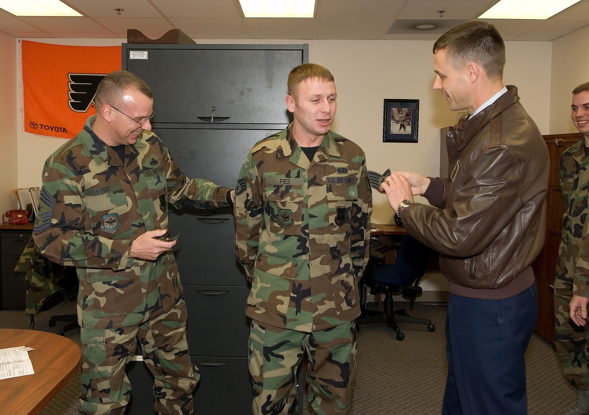 Col. Steve Harrison, 436th Airlift Wing commander, and Chief Master Sgt. John Woods, 436th AW command chief, prepare to "tack on" technical sergeant stripes on Staff Sgt. John Fies, 436th Communications Squadron, who was STEP promoted Dec. 21. (U.S. Air Force photo/ Jason Minto)