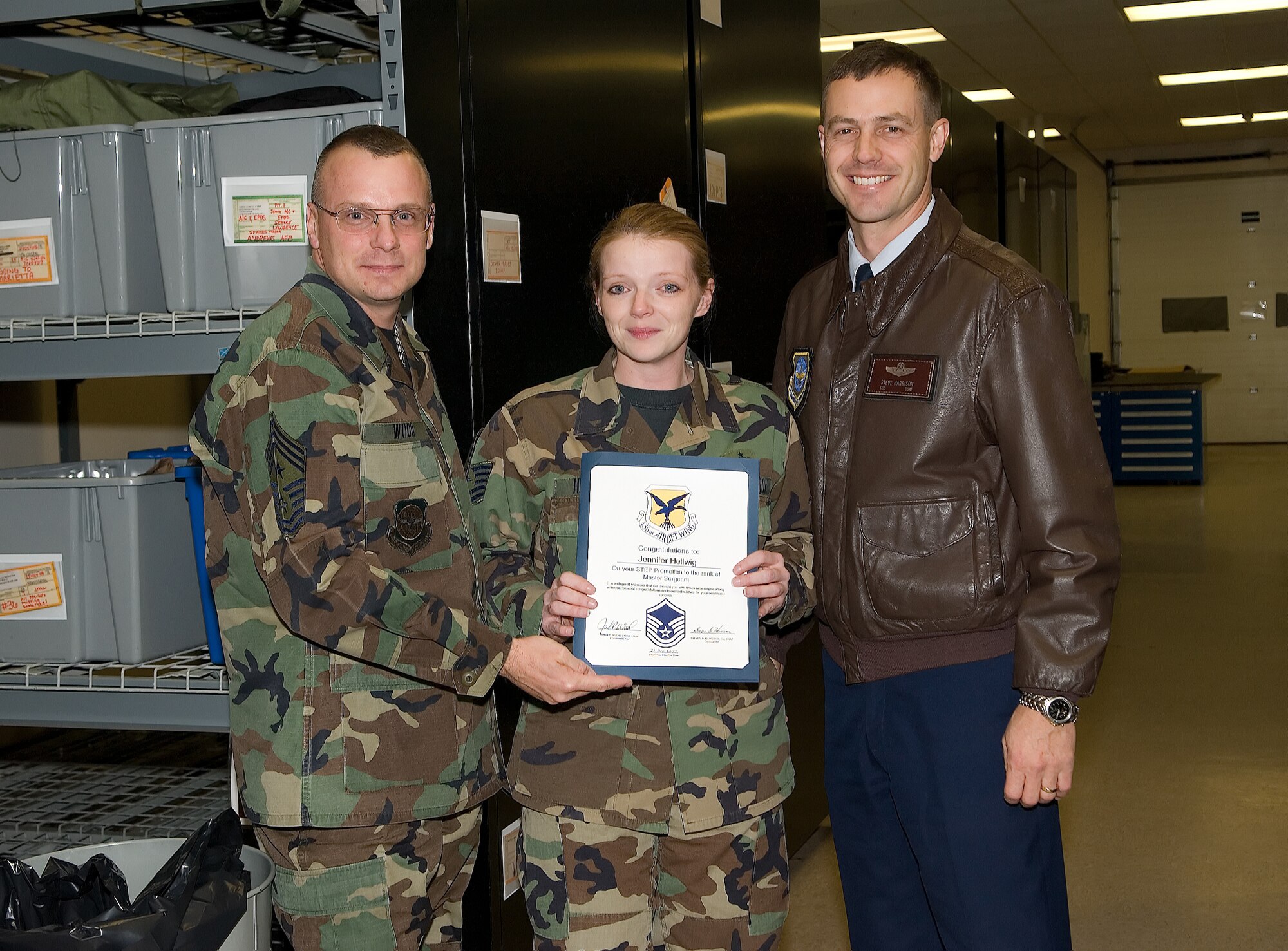 Tech. Sgt. Jennifer Hellwig, 436th Operations Support Squadron, smiles and poses with Col. Steve Harrison, 436th Airlift Wing commander, and Chief Master Sgt. John Wood, 436th AW command chief, who surprised her with a STEP promotion to the rank of master sergeant Dec. 21. (U.S. Air Force photo/ Jason Minto)