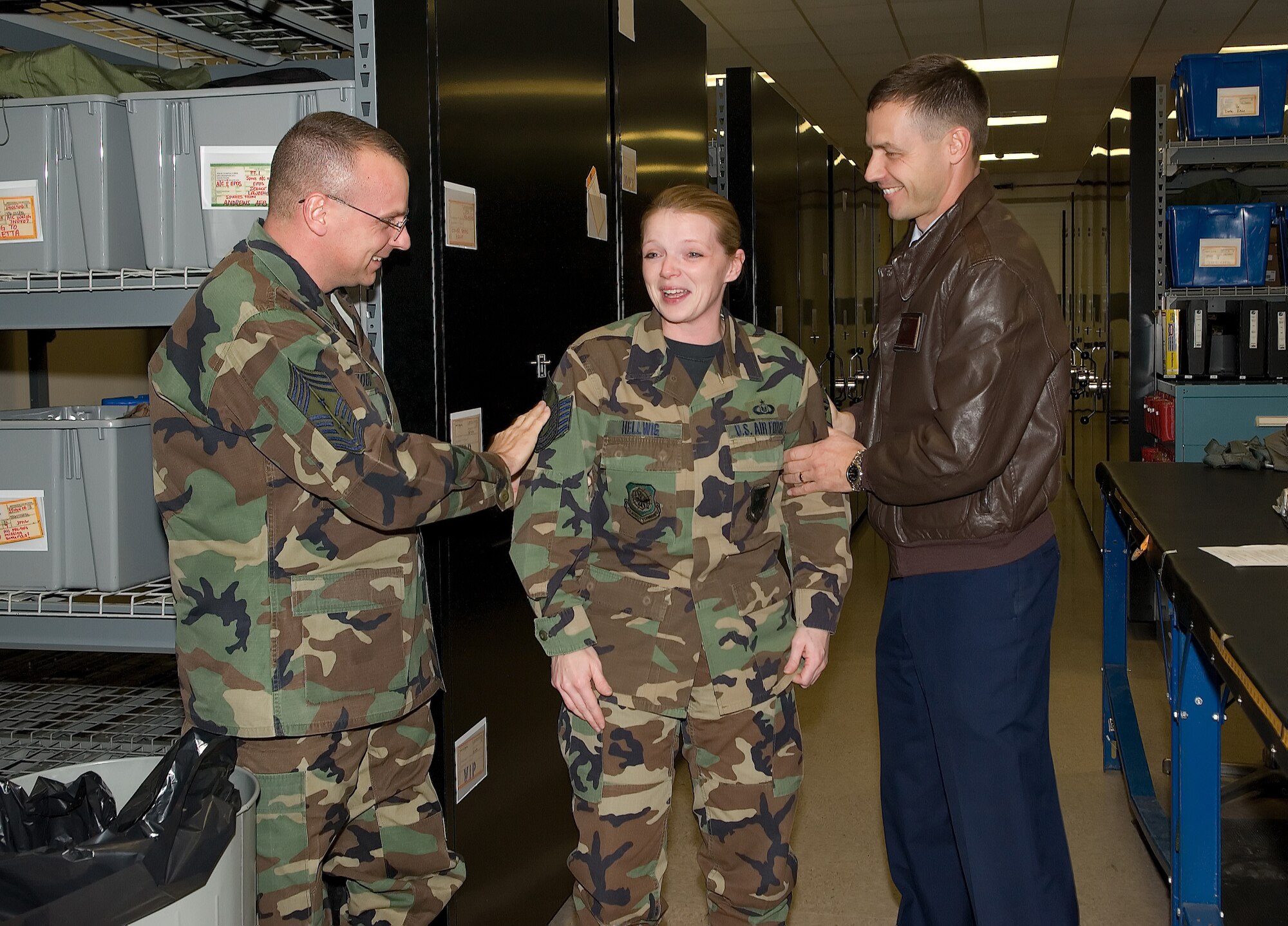 Tech. Sgt. Jennifer Hellwig, 436th Operations Support Squadron, smiles as Col. Steve Harrison, 436th Airlift Wing commander, and Chief Master Sgt. John Wood, 436th AW command chief "tack her on" during a surprise STEP promotion to the rank of master sergeant Dec. 21. (U.S. Air Force photo/ Jason Minto)
