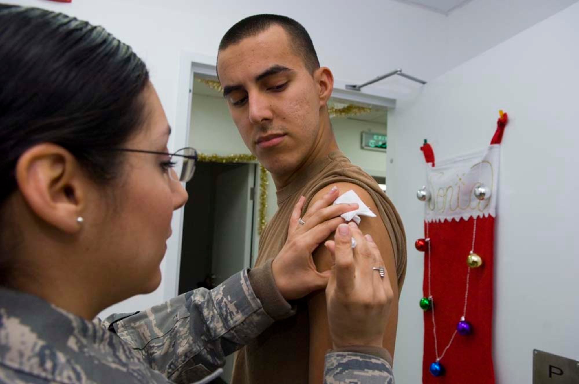 BALAD AIR BASE, Iraq -- Senior Airman Sonia Vega, a 332nd Expeditionary Aerospace Medical Squadron medical technician, administers the typhoid vaccination to Senior Airman Jedediah Villanueva, a 332nd Expeditionary Maintenance Squadron conventional maintainer, at the Air Force Clinic here, Dec. 27. Airman Vega is deployed from Barksdale Air Force Base, La., and Airman Villanueva is deployed from Spangdahlem Air Base, Germany. (U.S. Air Force photo/Staff Sgt. Travis Edwards)