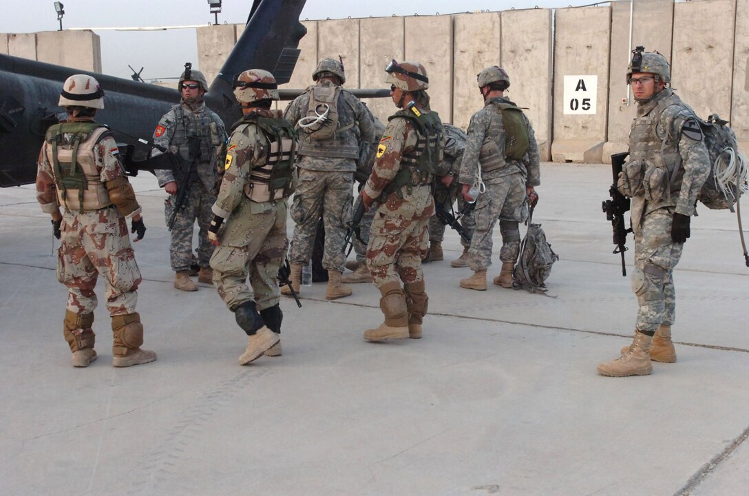 U.S. soldiers from Company A of the 2nd Battalion, 8th Cavalry Regiment, and Iraqi soldiers from the 3rd Brigade, 9th Iraqi Army Division (Mechanized), prepare for an air assault June 2, 2007, at Camp Taji, Iraq. Through joint operations such as air assaults, Ironhorse Brigade troops contributed to the capture of 86 high-ranking insurgent cell leaders and the finding of 180 weapons caches during their 15-month deployment. Photo by Staff Sgt. Jon Cupp, USA