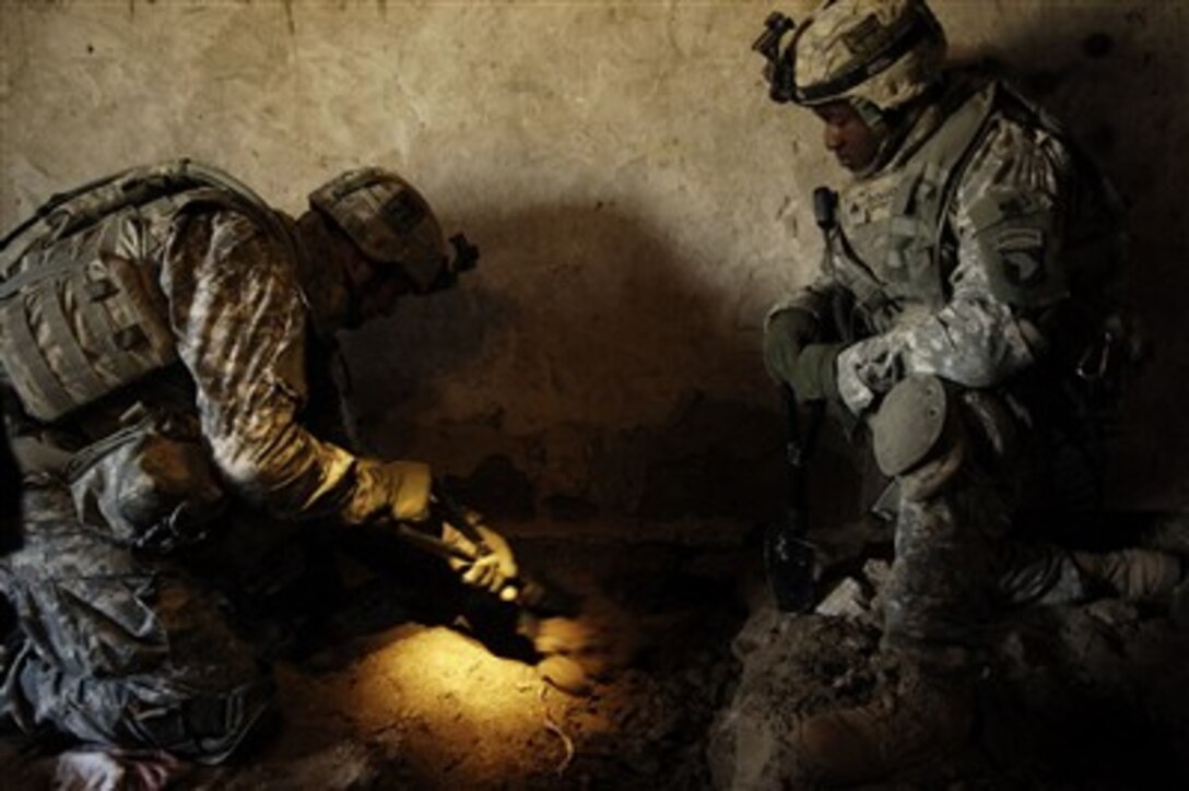 U.S. Army Sgt. Robert Anderson (left) digs as Sgt. Justin Bohannon waits his turn as they search the home of a suspected insurgent in Owesat, Iraq, on Dec. 18, 2007.  Soldiers of the 3rd Battalion, 187th Infantry Regiment, 3rd Brigade Combat Team, 101st Airborne Division, searched the home after a Concerned Local Citizen checkpoint was attacked by a suicide bomber and small arms fire.  