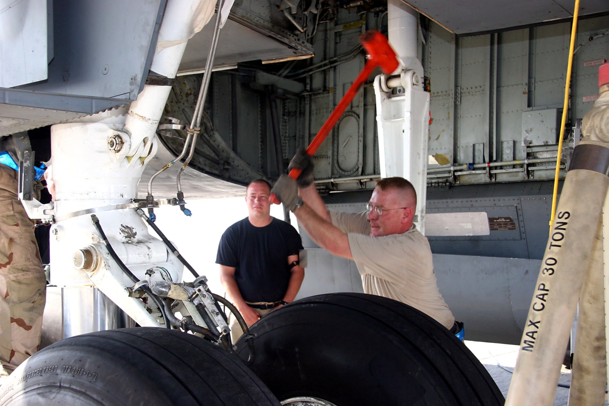 Tech. Sgt. Nathan Darnell (left) observes as Tech. Sgt. James Bernardo carefully lowers the main landing gear strut on a KC-135 Stratotanker to full extension using an 11.5 pound dead blow hammer Dec. 21. The Airmen are assigned to the 380th Expeditionary Aircraft Maintenance Squadron and deployed from the 22nd Aircraft Maintenance Squadron at McConnell Air Force Base, Kansas. (U.S. Air Force photo/Master Sgt. Ruby Zarzyczny) 