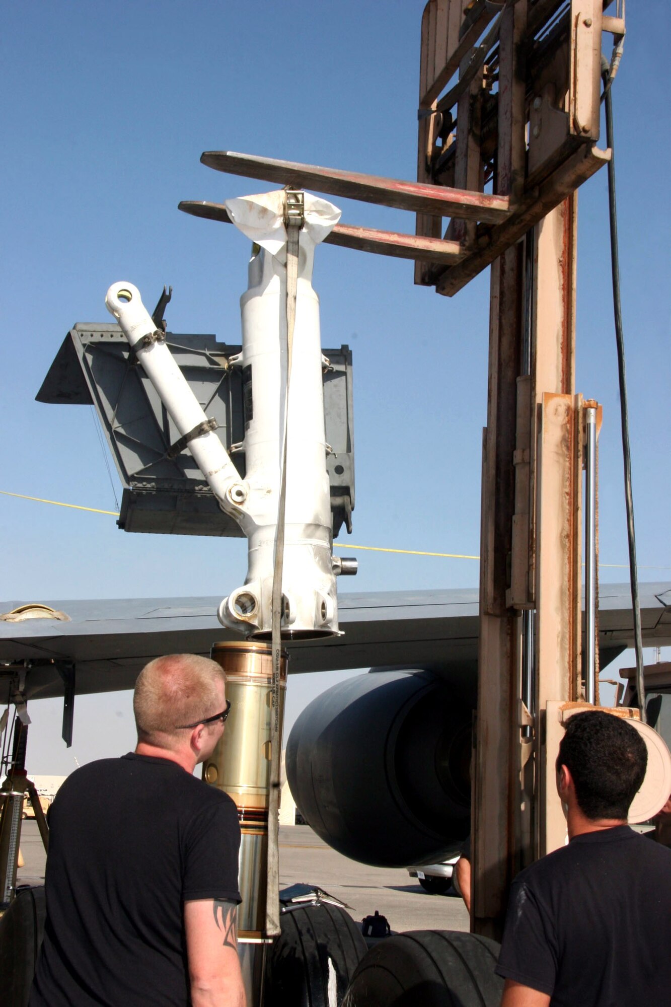 Senior Airman Kyle Beisner (left) and Tech. Sgt. Eric Hunt spot Tech. Sgt. Jeremy Polk, the forklift driver, as he reinstalls a KC-135 Stratotanker landing gear strut Dec. 21.  The Airmen are assigned to the 380th Expeditionary Aircraft Maintenance Squadron and deployed from the 22nd Aircraft Maintenance Squadron at McConnell Air Force Base, Kansas. (U.S. Air Force photo/Master Sgt. Ruby Zarzyczny) 