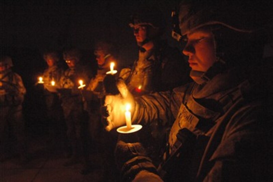 U.S. Army soldiers from Bravo Battery, 2nd Battalion, 32nd Field Artillery Regiment, attached to 2nd Brigade Combat Team, take part in a candlelight ceremony during a Christmas party at Joint Security Station Torch in Yarmuk, Iraq, on Dec. 25, 2007.  