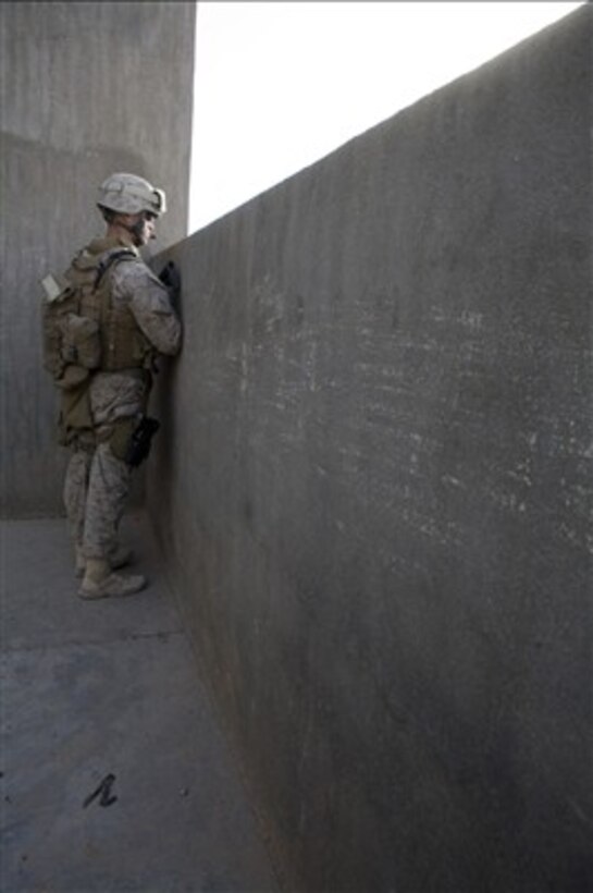 U.S. Marine Corps Cpl. Jonathan Rogers peers over a wall as he observes an area in Iraq on Dec. 15, 2007.  Rogers and his fellow Marines with 1st Platoon, Lima Company, 3rd Battalion, 2nd Marine Regiment, Regimental Combat Team 2 patrol each day to ensure security in their area.  