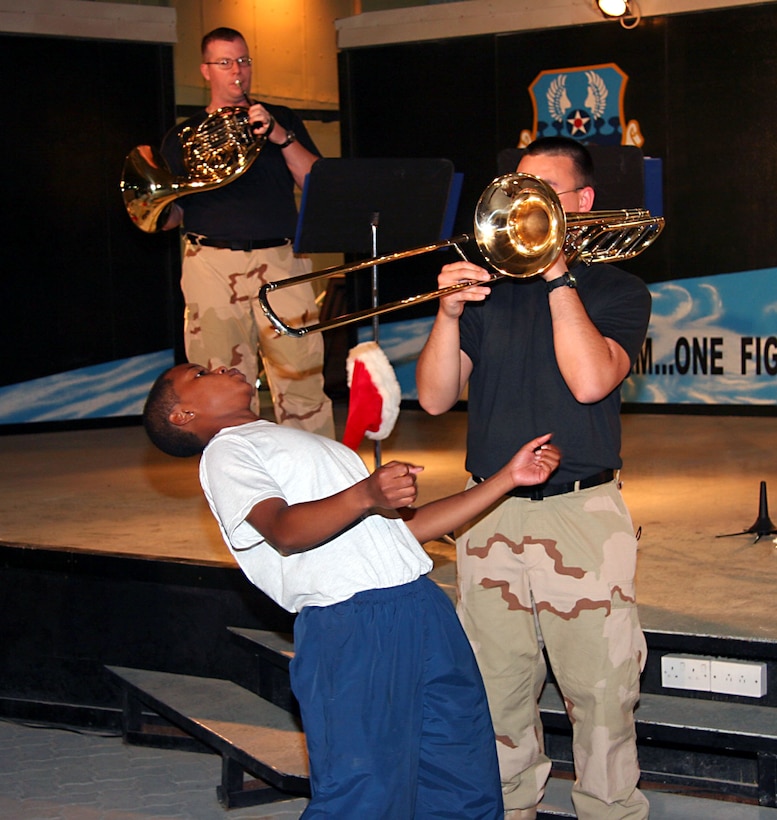 Members of the USAF CENTAF Band's "Hot Brass" entertain troops in Southwest Asia.  SrA Kaz Kruszewski uses his trombone as a make-shift limbo stick during a performance.  Hot Brass is from the USAF Band of Flight at Wright Patterson AFB, OH.  Members include TSgt Eric Knorr (trumpet and NCOIC,) TSgt John Rider (tuba,) SSgt Jason Plosch (trumpet,) SrA Kaz Kruszewski (trombone,) SrA VJ Russell (horn,) and MSgt Bob Green (percussion.)  Photos by MSgt Ruby Zarzyczny.