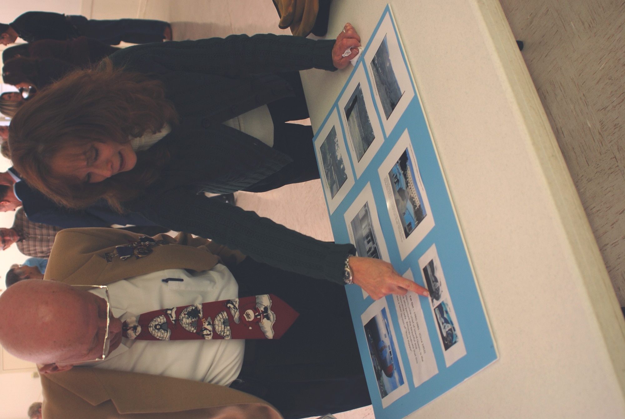 Tanya Kennert shows her father, Purple Heart and Prisoner of War medals receipient, Franklin Henry Hall, a collage of photos she assembled depicting special times during his military service:  his B-29 called "The Cat Girl", and the bridge he walked across to freedom after 11 months as a prisoner of war in Korea.  (U.S. Air Force Photo/Laura Dermarderosian-Smith)