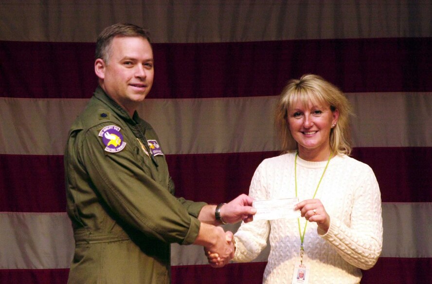 Lt. Col. Craig Trammell, 96th Airlift Squadron commander, presents a check of $400 to Shirlee Peterson, the director of recreation at the veterans home in St. Paul.  The money, which was gathered from a collection from 96th AS members, was used to buy Christmas presents for the veterans. Air Force Photo/Staff Sgt. Michael Edmond