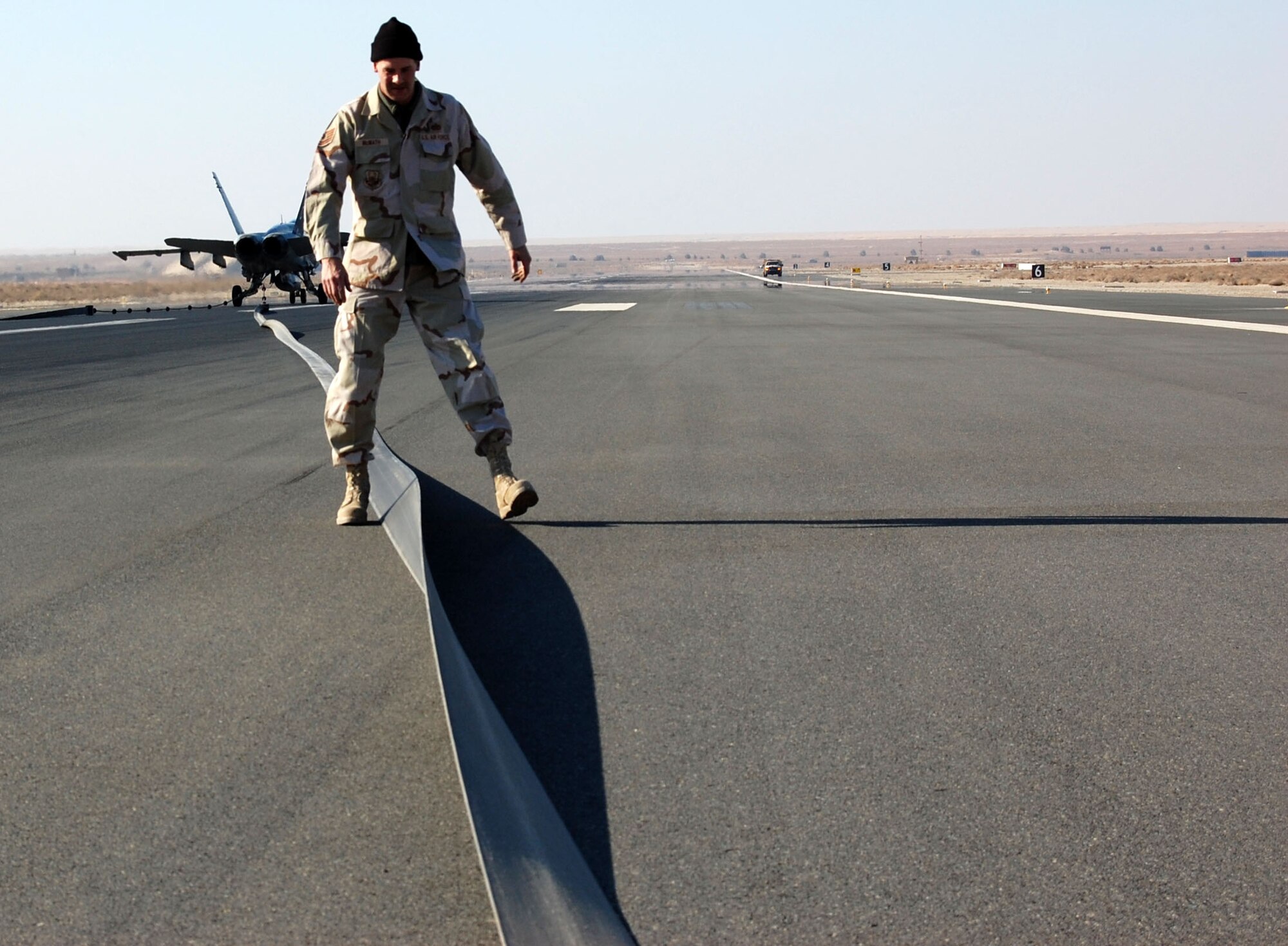 SOUTHWEST ASIA – Tech. Sgt. Mike McMath walks the tape after the barrier was engaged Dec. 27 at an air base in the Middle East. Post barrier inspections are used to ensure there is no damage to the tape before being returned to service. Sergeant McMath is a 386th Civil Engineer Squadron barrier maintenance technician from the Portland Air National Guard, Ore. (Air Force photo\Staff Sgt. Phillip Butterfield)