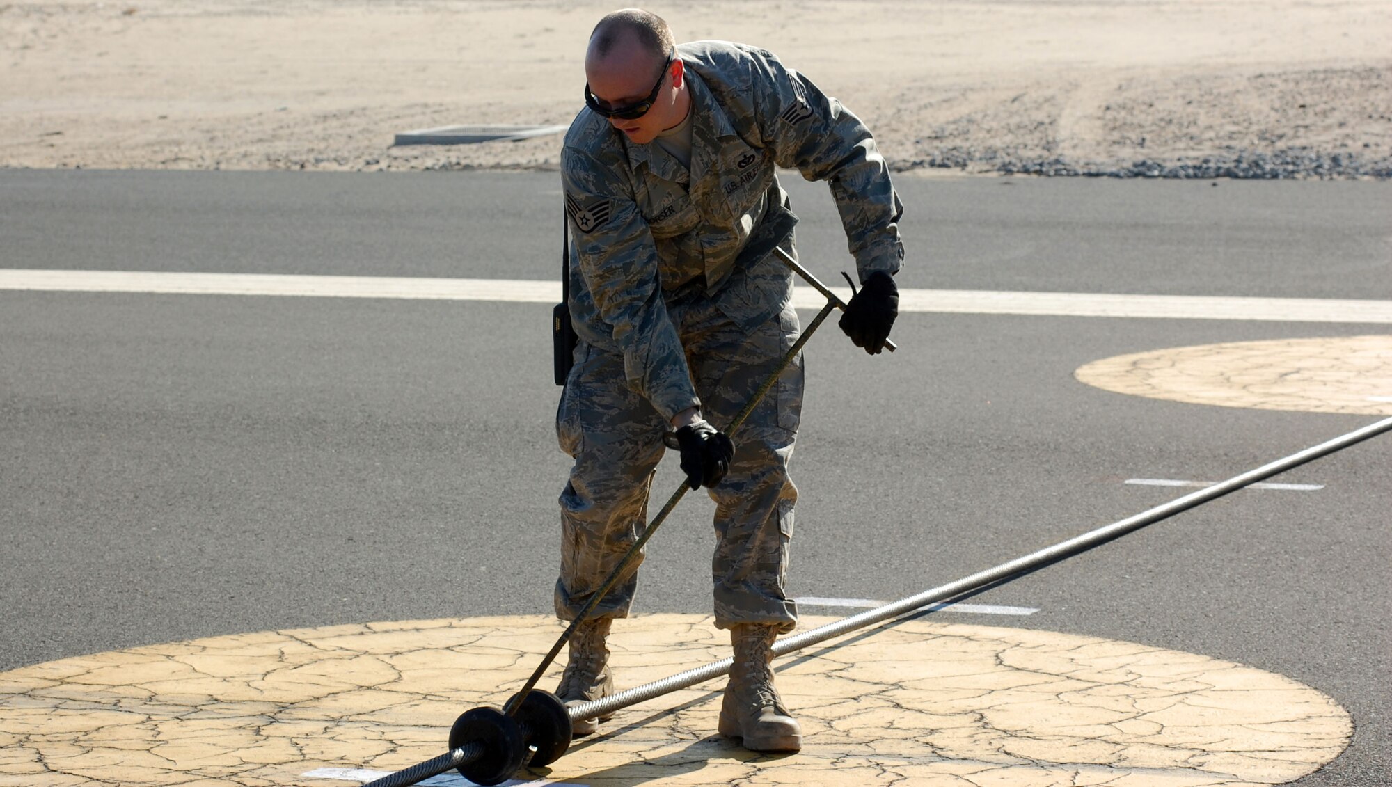 SOUTHWEST ASIA – Staff Sgt. Michael Corser, pulls rubber support discs to predetermined spaces Dec. 27 at an air base in the Middle East. The rubber discs are used to align the barrier cable with the tail hook on aircraft. Sergeant Corser is a 386th Civil Engineer Squadron barrier maintenance technician from Langley Air Force Base, Va. (Air Force photo\Staff Sgt. Phillip Butterfield)