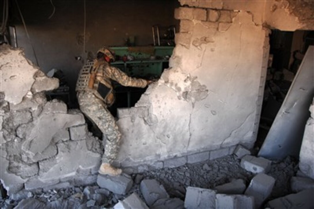 A U.S. Army soldier climbs over the remainder of a wall as he investigates a house destroyed by a bomb in Mosul, Iraq, on Dec. 25, 2007.  The soldier is attached to the 3rd Armored Cavalry Regiment.  