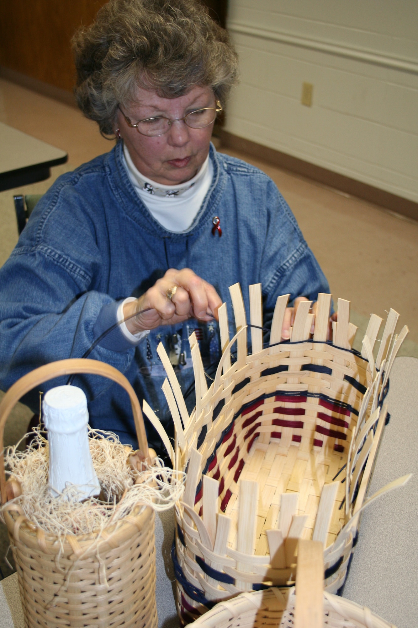 Colonel Sue Yingling, retired, intertwines reeds to create a basket at the Community Activity Center.  Ms. Yingling offers a class in basketweaving at the CAC. (U.S. Air Force Photo/Adrian McCandless)