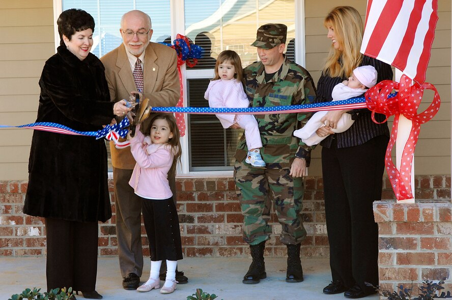 Kathryn Thompson, managing director of American Eagle Communities, helps Lowell Klepper, 23rd CES deputy base civil engineer and Brianna McKay, cut the ribbon on her family’s new home Jan. 31. Brianna is the daughter of Tech. Sgt. Martin and Maria McKay. The family will be  moving into the three-bedroom 1,630 square-foot home as soon as community projects are completed.  (U.S. Air Force photo by Airman 1st Class Gina Chiaverotti)  
