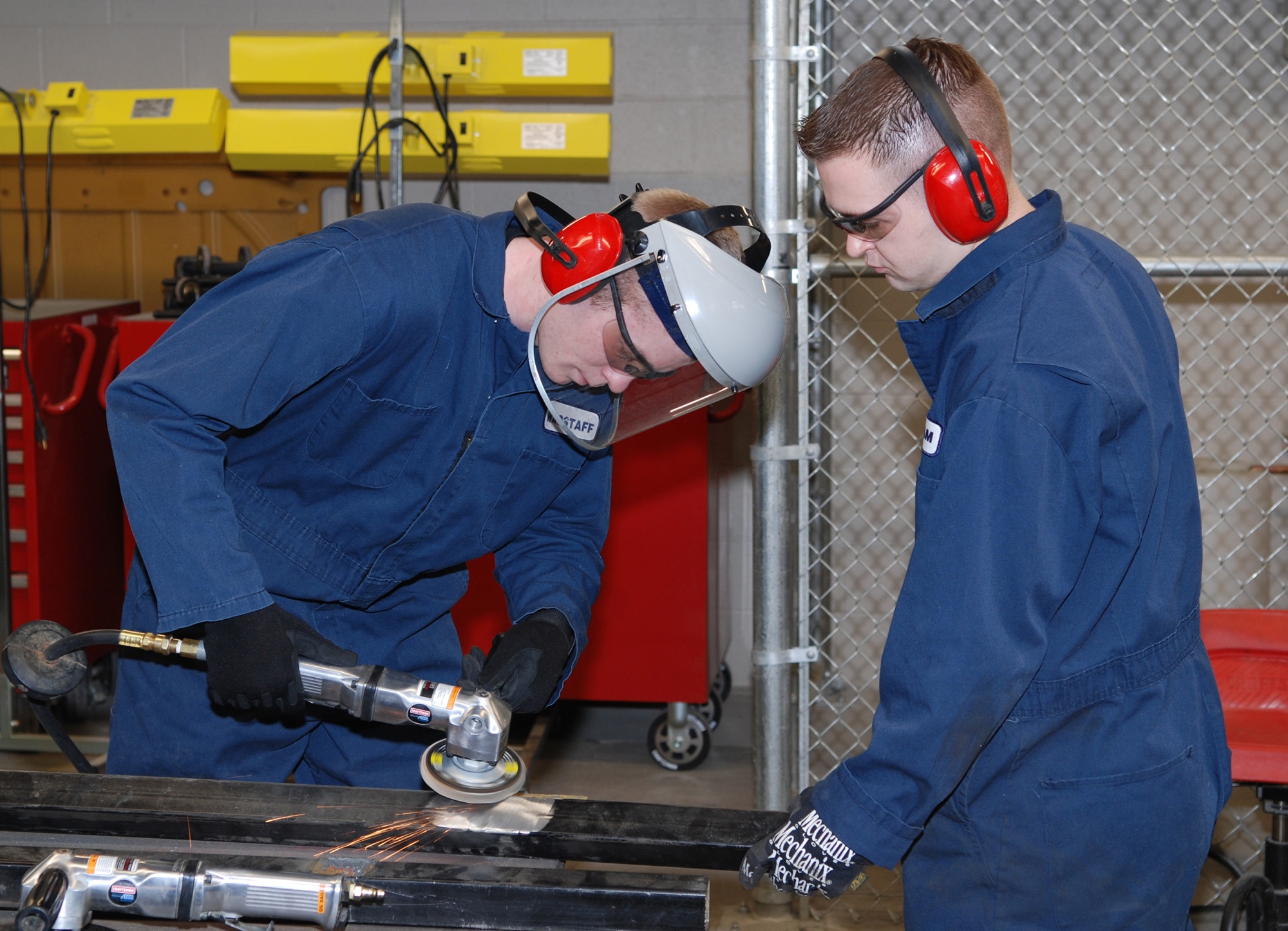 Airman Kirk Wagstaff, 92nd Logistics Readiness Squadron vehicle body mechanic, and Staff Sgt. Chris Statham, 92nd LRS customer service NCOIC, fabricate passenger seating for alert crew vehicles. Sergeant Statham is teaching Airman Wagstaff how to grind the metal down so that it is ready to be welded. Sergeant Statham has been at Fairchild for nine months, arriving from Kunsan, Korea, while Airman Wagstaff has been here for five months and is straight out of technical training.