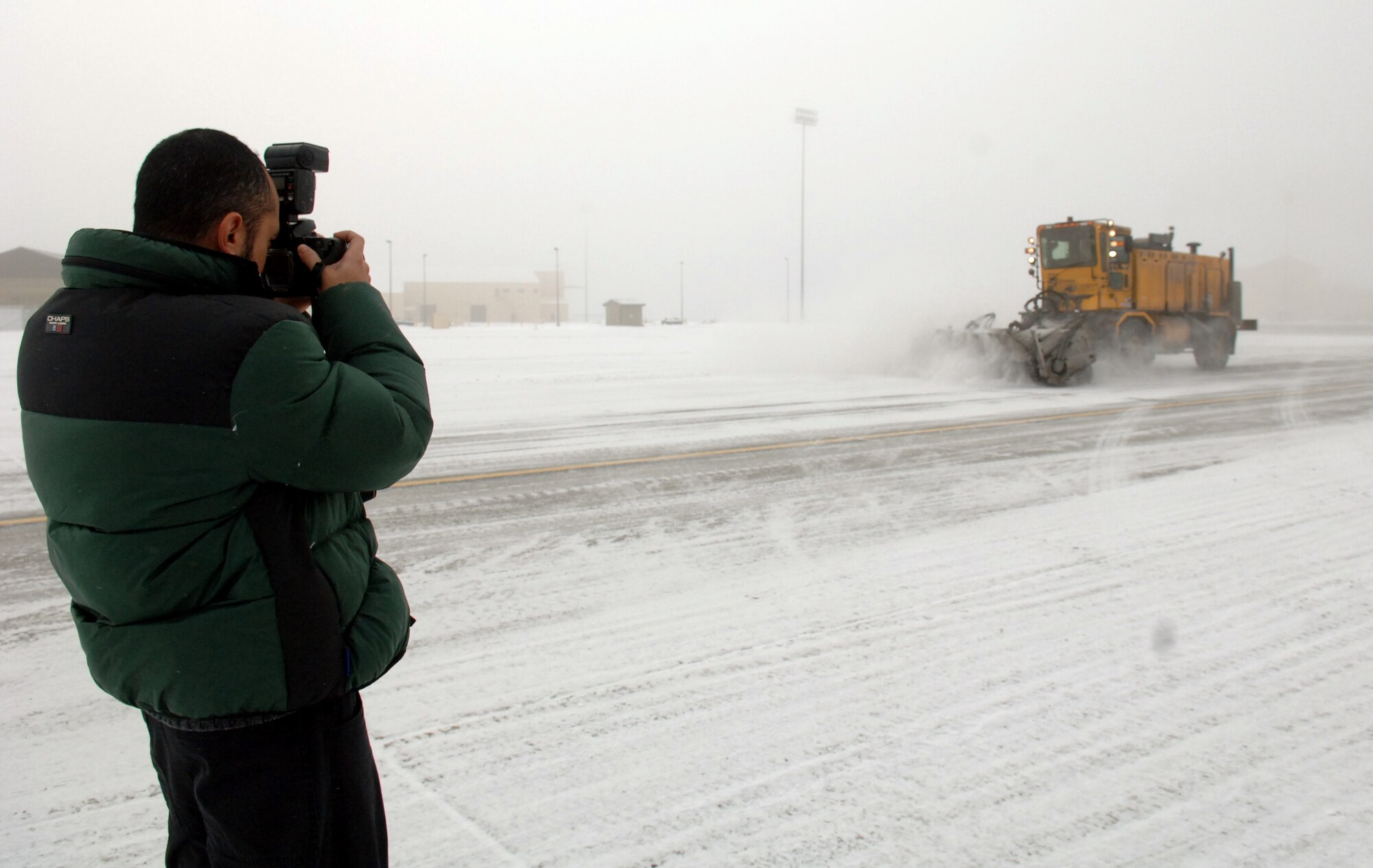 Juan Villeges, member of the film crew from Tyndall AFB, Fla., documents a snow removal operation on the flightline Tuesday for a snow removal training aid that is currently being producing for the Air Force. The new Web-based training module will replace an outdated 20-year-old video. (U.S. Air Force photo by Senior Airman Jessica Fuentez)