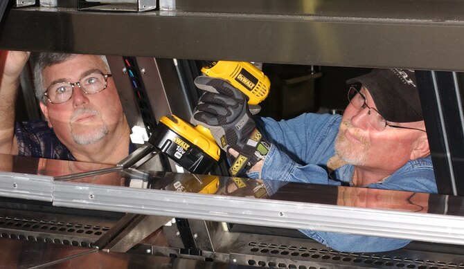 Commissary employees Don Cauthen, left, and Sean O’Neill put finishing touches to a deli display case.  (U.S. Air Force photo by Kemberly Groue)                             