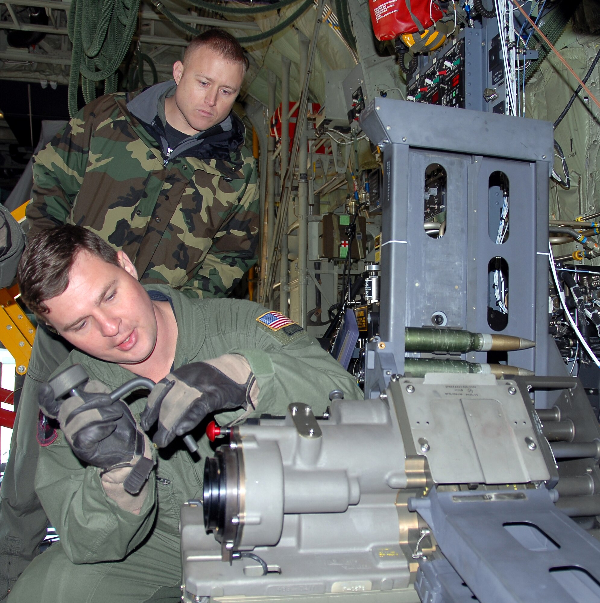 Technical Sgt. Ben Filek works on a newly-installed 30 mm Bushmaster cannon aboard an AC-130U Spooky gunship as Technical Sgt. James Knight looks on.  Both Airmen are aerial gunners with the 19th Special Operations Squadron at Hurlburt Field, Fla.  The 30 mm gun will eventually replace both the 40 mm cannon and 25 mm gun on U-model gunships. (Air Force photo by Chief Master Sgt. Gary Emery)