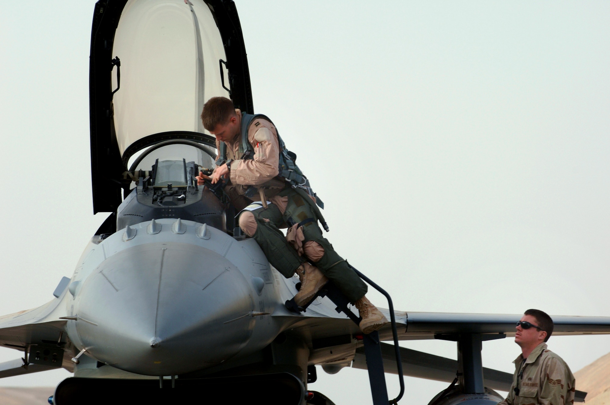 Capt. William Lutmer climbs into an F-16 Fighting Falcon while Senior Airman Skylar Mims assists him Jan. 29 at Balad Air Base, Iraq. Captain Lutmer is deployed to the 332nd Air Expeditionary Wing as part of the 14th Expeditionary Fighter Squadron. Airman Mims is a crew chief for the 14th Expeditionary Aircraft Maintenance Squadron. The 14th Fighter Squadron is deployed from Misawa Air Base, Japan. (U. S. Air Force photo/Staff Sgt. Michael R. Holzworth)

