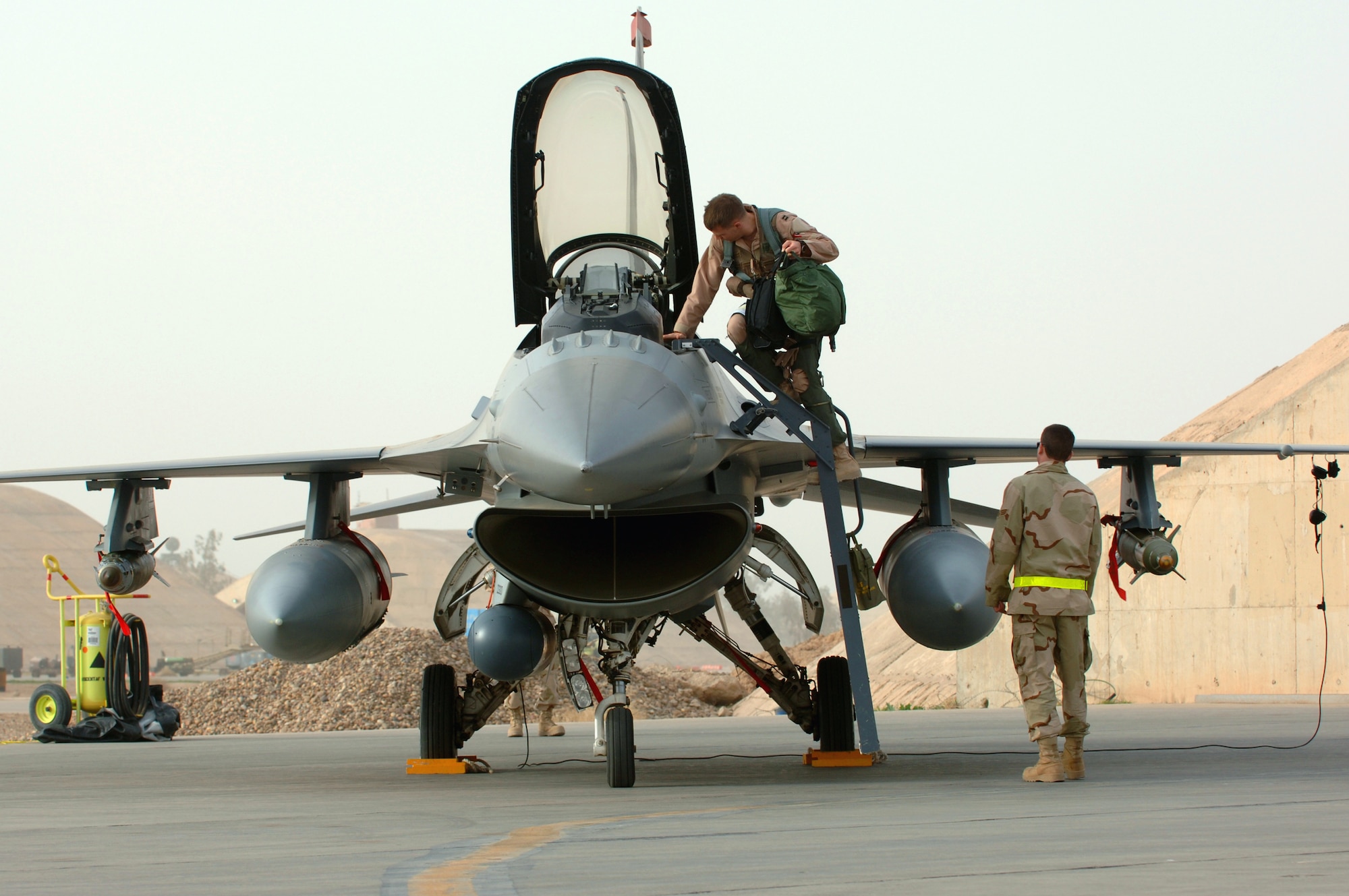 Capt. William Lutmer climbs into an F-16 Fighting Falcon while Senior Airman Skylar Mims assists him Jan. 29 at Balad Air Base, Iraq. Captain Lutmer is deployed to the 332nd Air Expeditionary Wing as part of the 14th Expeditionary Fighter Squadron. Airman Mims is a crew chief for the 14th Expeditionary Aircraft Maintenance Squadron. The 14th Fighter Squadron is deployed from Misawa Air Base, Japan. (U. S. Air Force photo/Staff Sgt. Michael R. Holzworth)
